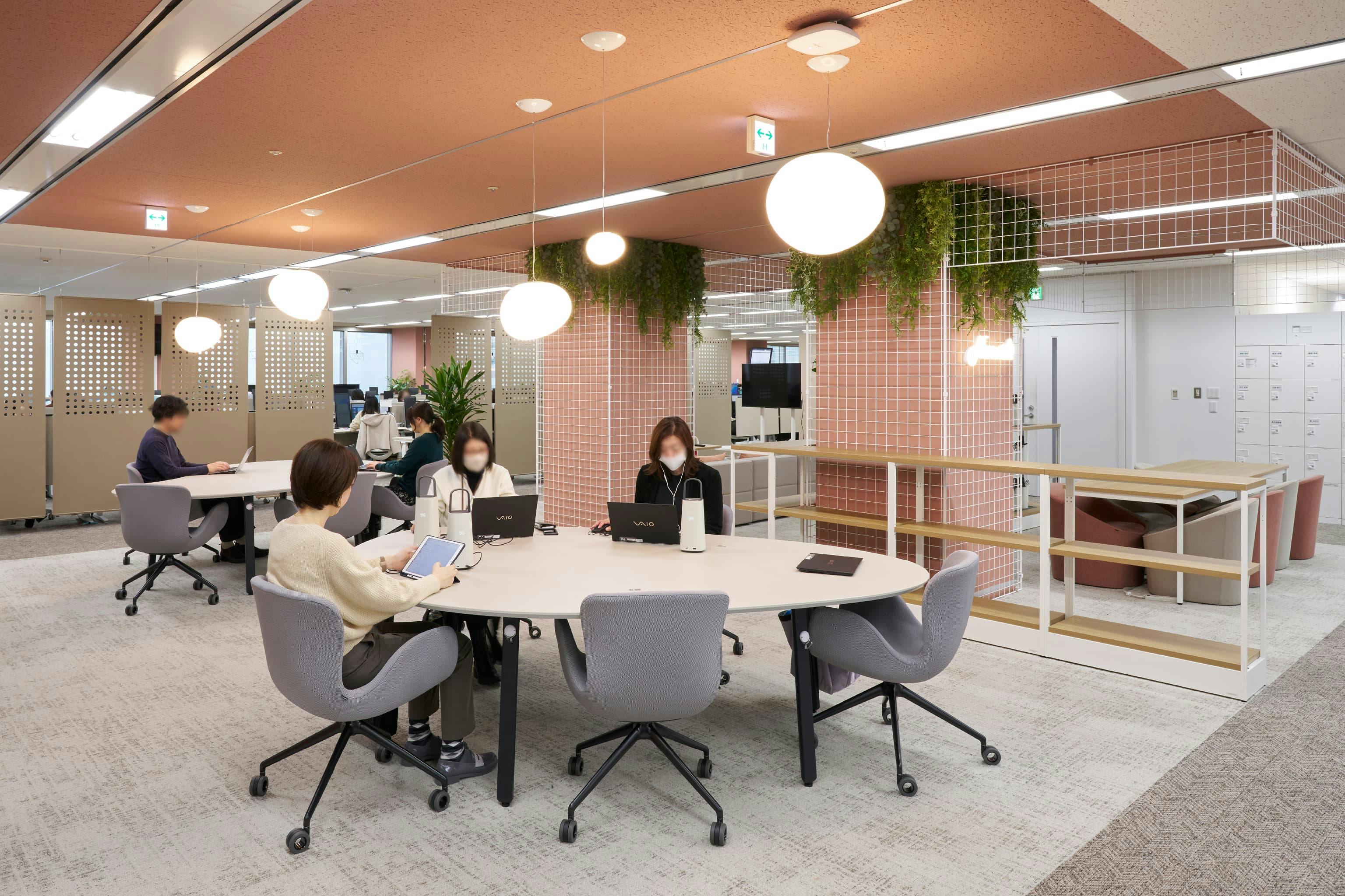 株式会社JALナビア 様の事例写真／[18F Nexus]執務席としても利用されるオープンエリア。柱を囲うメッシュパネルに取り付けられた植栽が、居心地が良くコミュニケーションを取りやすい空間を演出します。