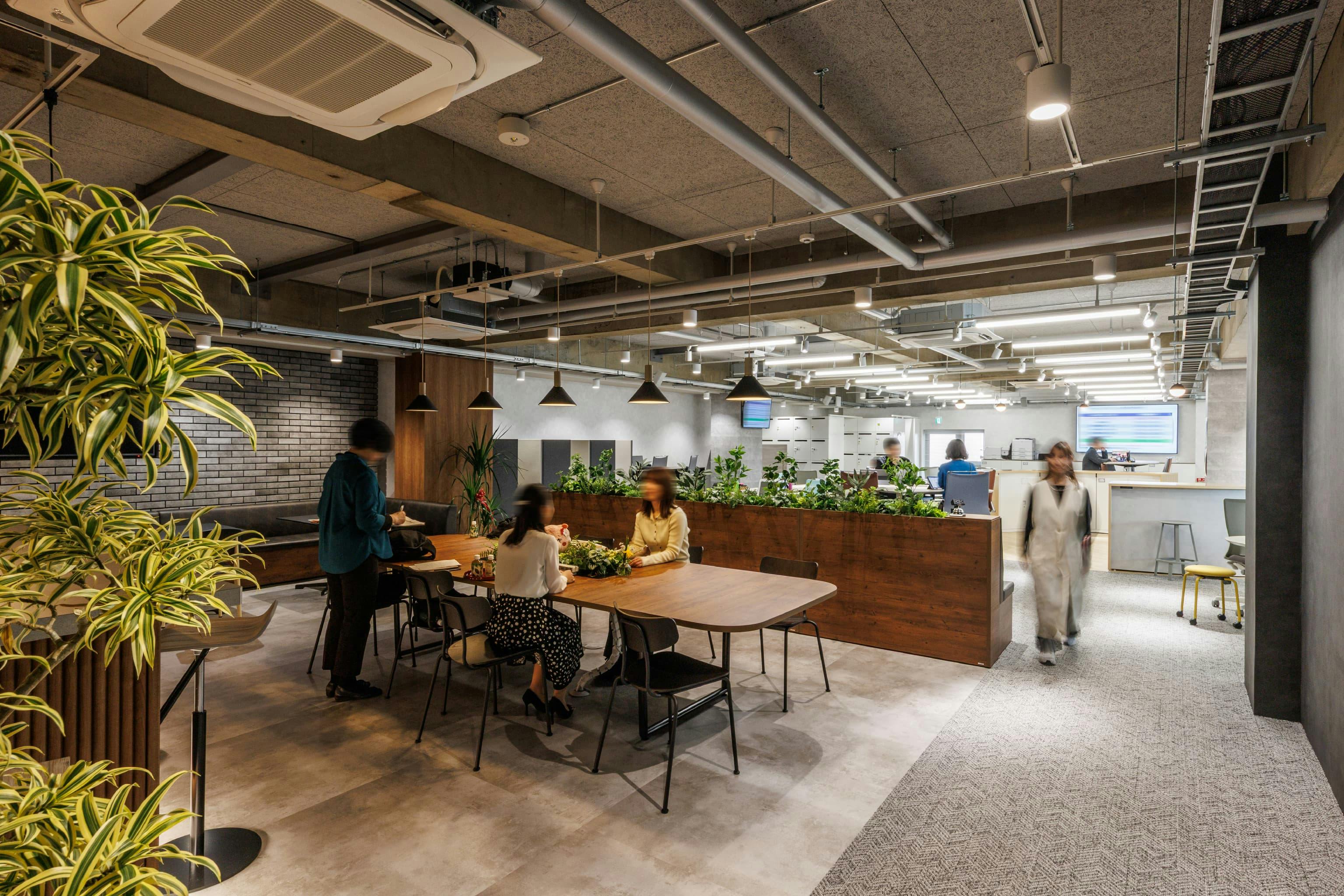 トヨタユナイテッド奈良株式会社 様の事例写真／[2Fカフェスペース「Oasis」]階段を上がったところに現れるカフェスペース「Oasis」。奥の執務エリアとは照明や壁、家具のテイスト、さらに床材を貼り分けて雰囲気を変え、ゆるやかに空間を区切っています。