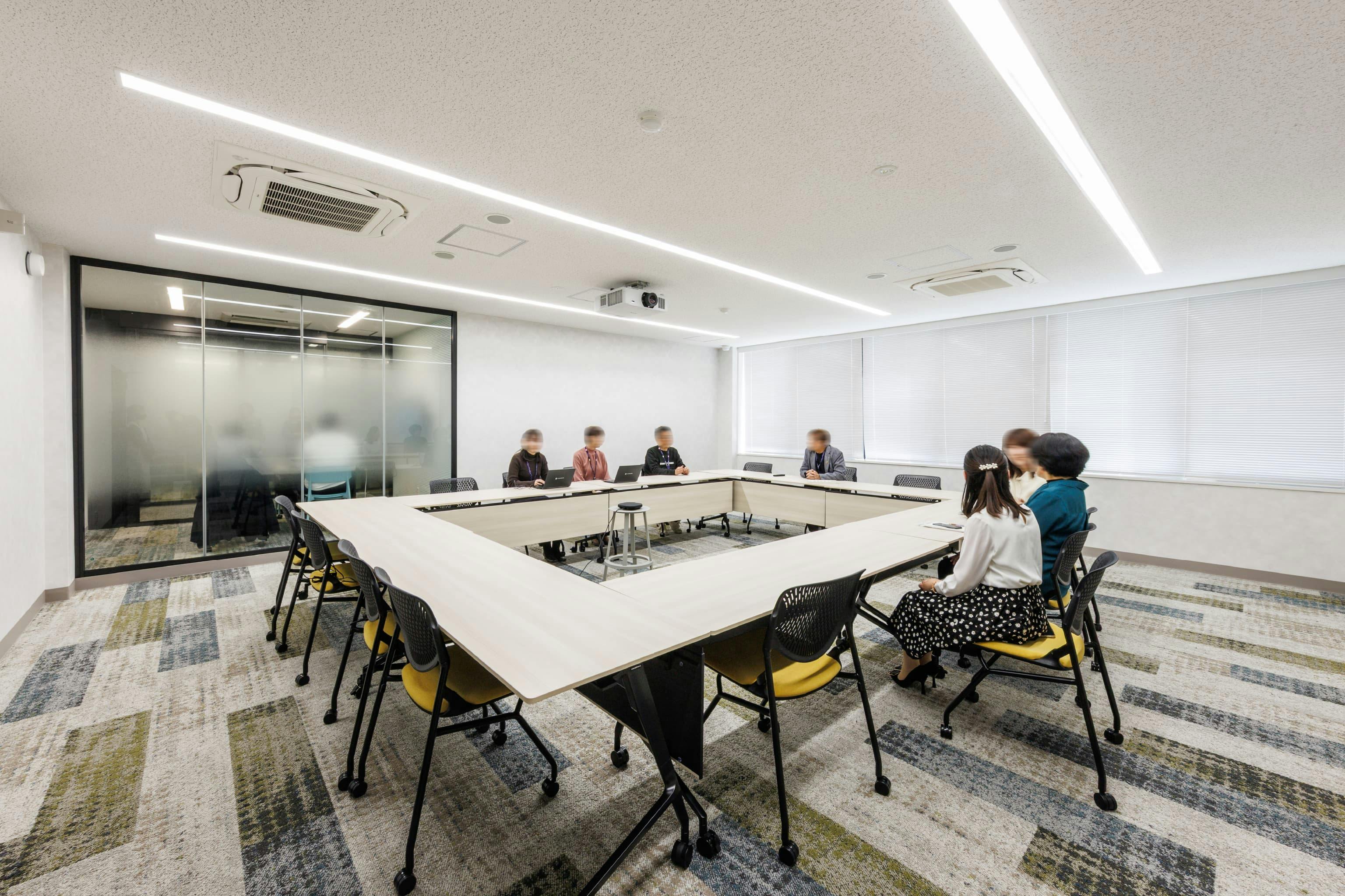 トヨタユナイテッド奈良株式会社 様の事例写真／[2F会議室（イエロー）]もっとも広く、最大16名が利用できるイエローの部屋。この会議室は、大勢が自由に発言し、議論を交わすことのできる活気に満ちた部屋になっています。カーペットや椅子の座面にも明るいイエローがあしらわれています。