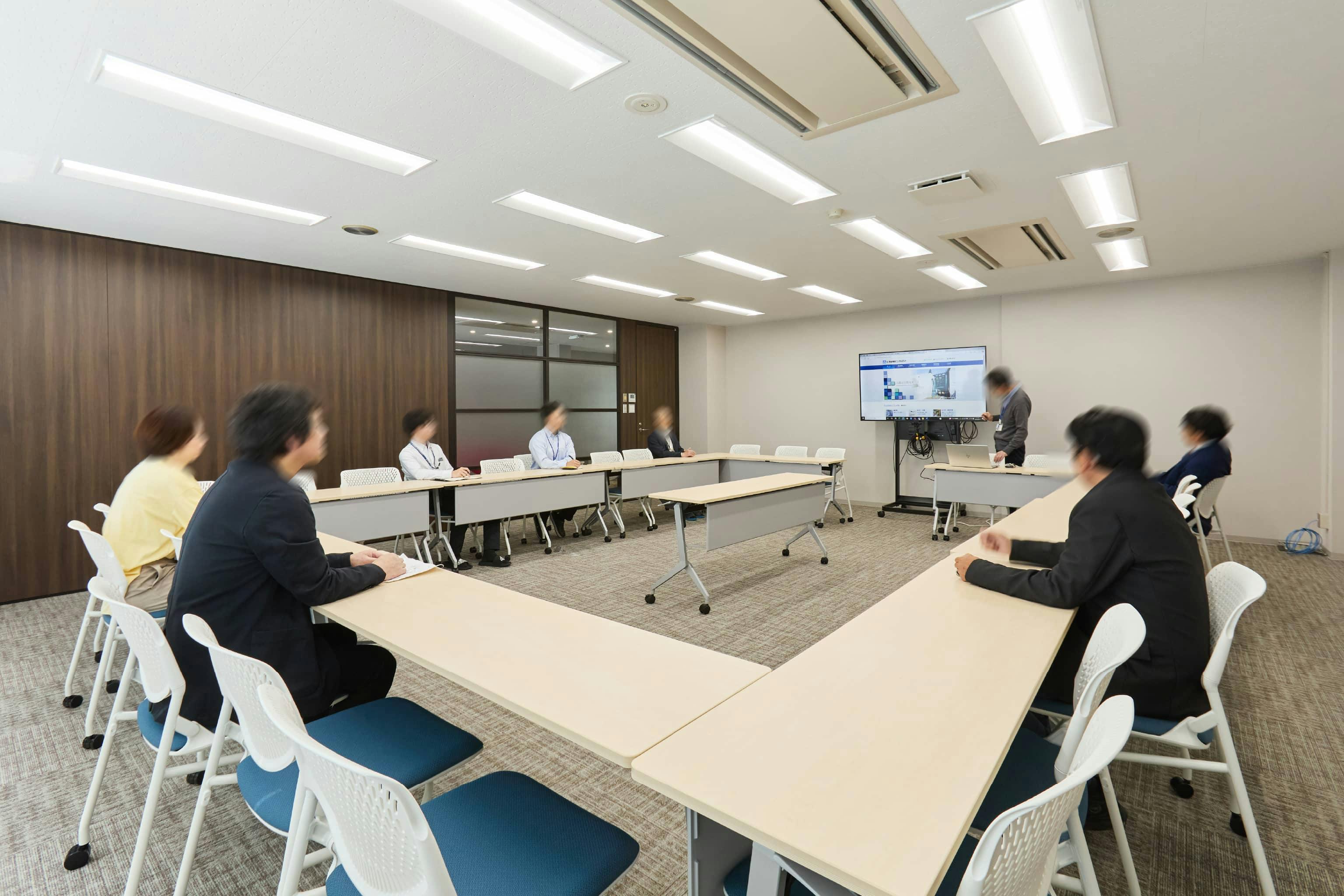 株式会社荒谷建設コンサルタント 様の事例写真／[1F会議室]30人収容可能な会議室。レイアウト変更がしやすいキャスター付きのテーブルとイス、大型モニターが置かれています。全社会議や外部とのミーティング等に利用されています。