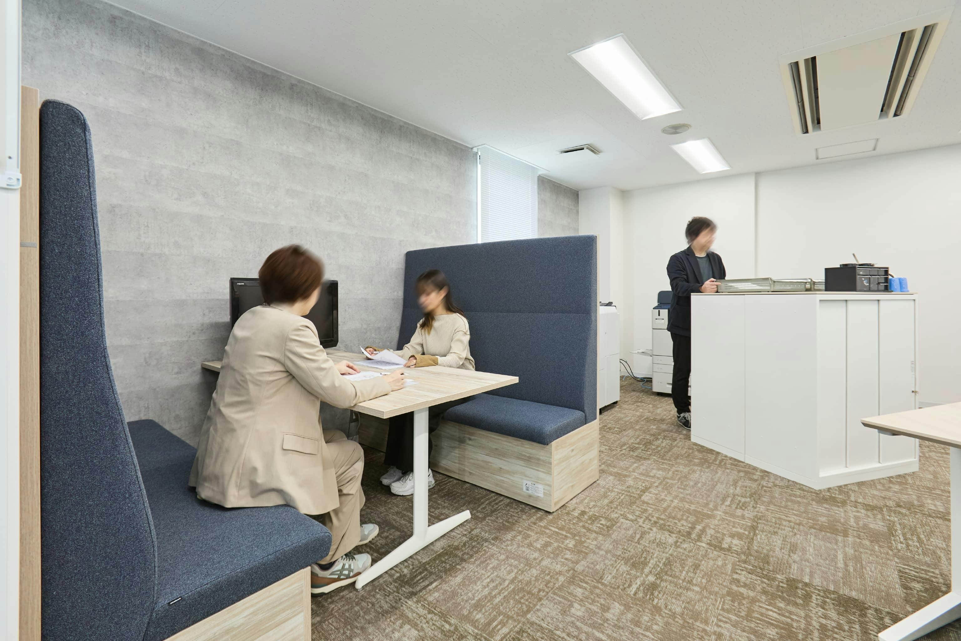 株式会社荒谷建設コンサルタント 様の事例写真／[2F執務スペース]壁際に設けられたファミレス席は、ソファの背が高くパーティションの役割を果たしており、セミプライベート空間のように使える人気の席です。会議室を使うほどではないけれど、集中して打ち合わせしたいときに利用されています。
