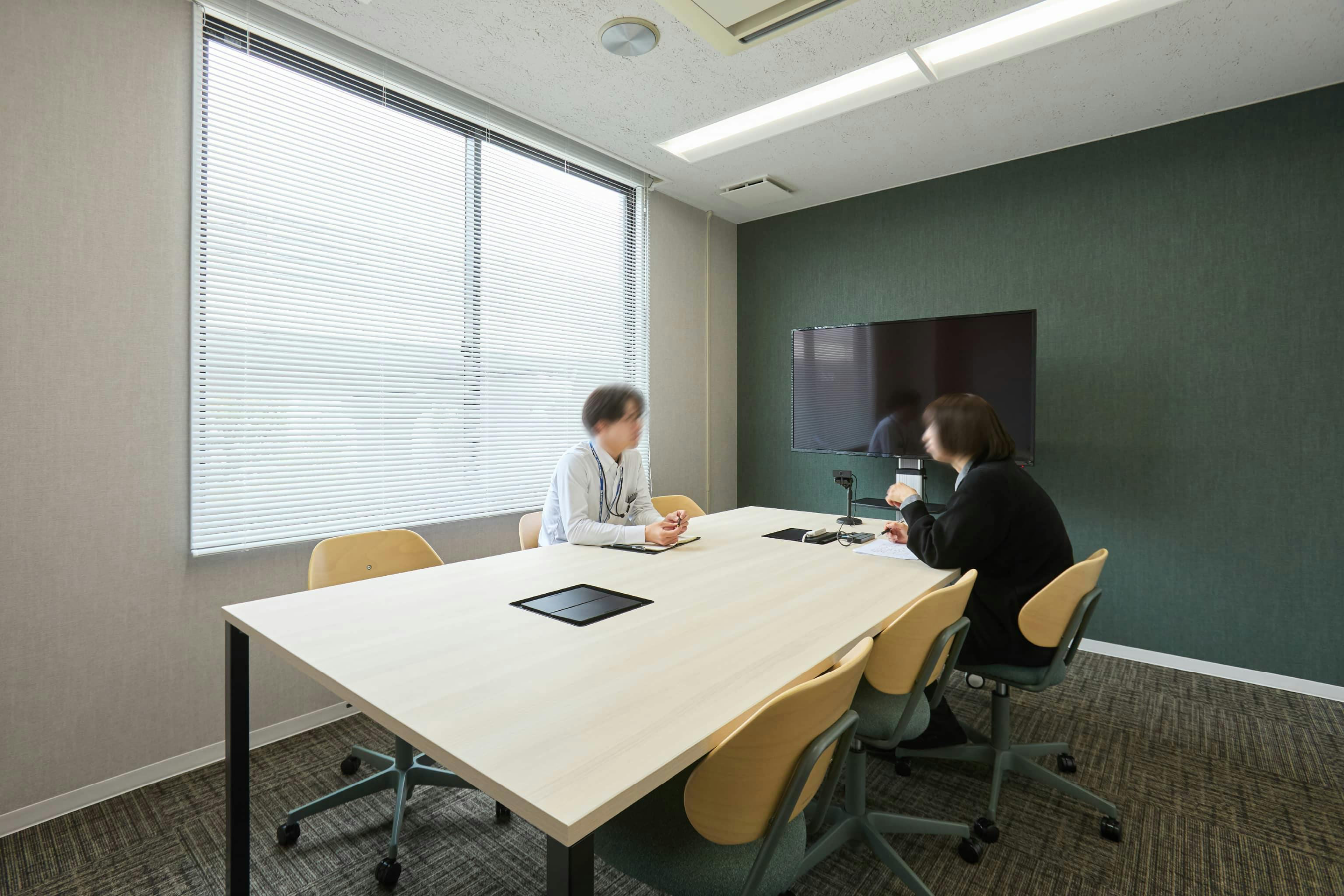 株式会社荒谷建設コンサルタント 様の事例写真／[2F会議室]執務スペースの横には、大きな窓から光が差し込む明るい会議室があります。壁の色はフロアごとに異なり、2階は自然の木々を連想させる深緑色。心が落ち着き、穏やかに議論を交わせそうです。