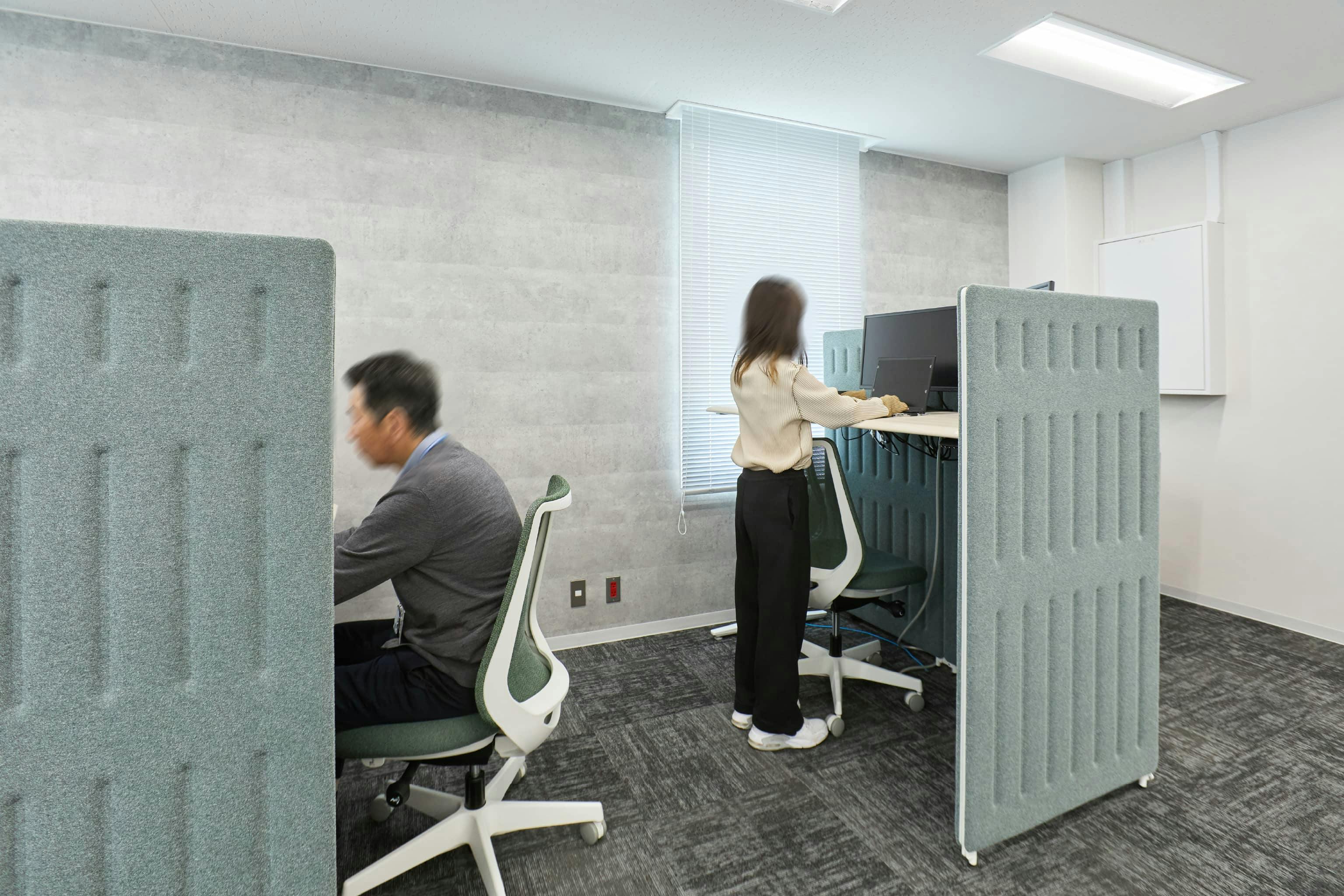 株式会社荒谷建設コンサルタント 様の事例写真／[4F執務スペース]部屋の奥には、電動昇降デスクを吸音パネルで囲ったソロワークブースが。立ち姿勢で働けるデスクは、座り過ぎと眠気を防ぎ、業務効率化にも一役かっています。