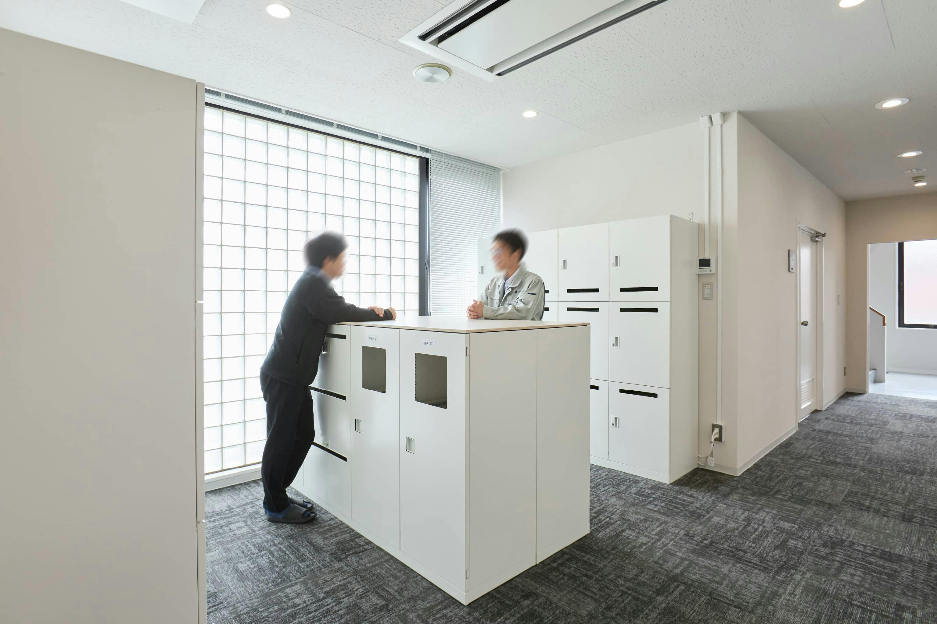 株式会社荒谷建設コンサルタント 様の事例写真／[4F個人ロッカー]かつて個人席にあったワゴンを廃止し、執務エリア近くの立ち寄りやすいスペースに個人ロッカーを集約。ガラスブロックから光が差し込む明るい空間で、利用がてら社員同士のコミュニケーションが生まれています。