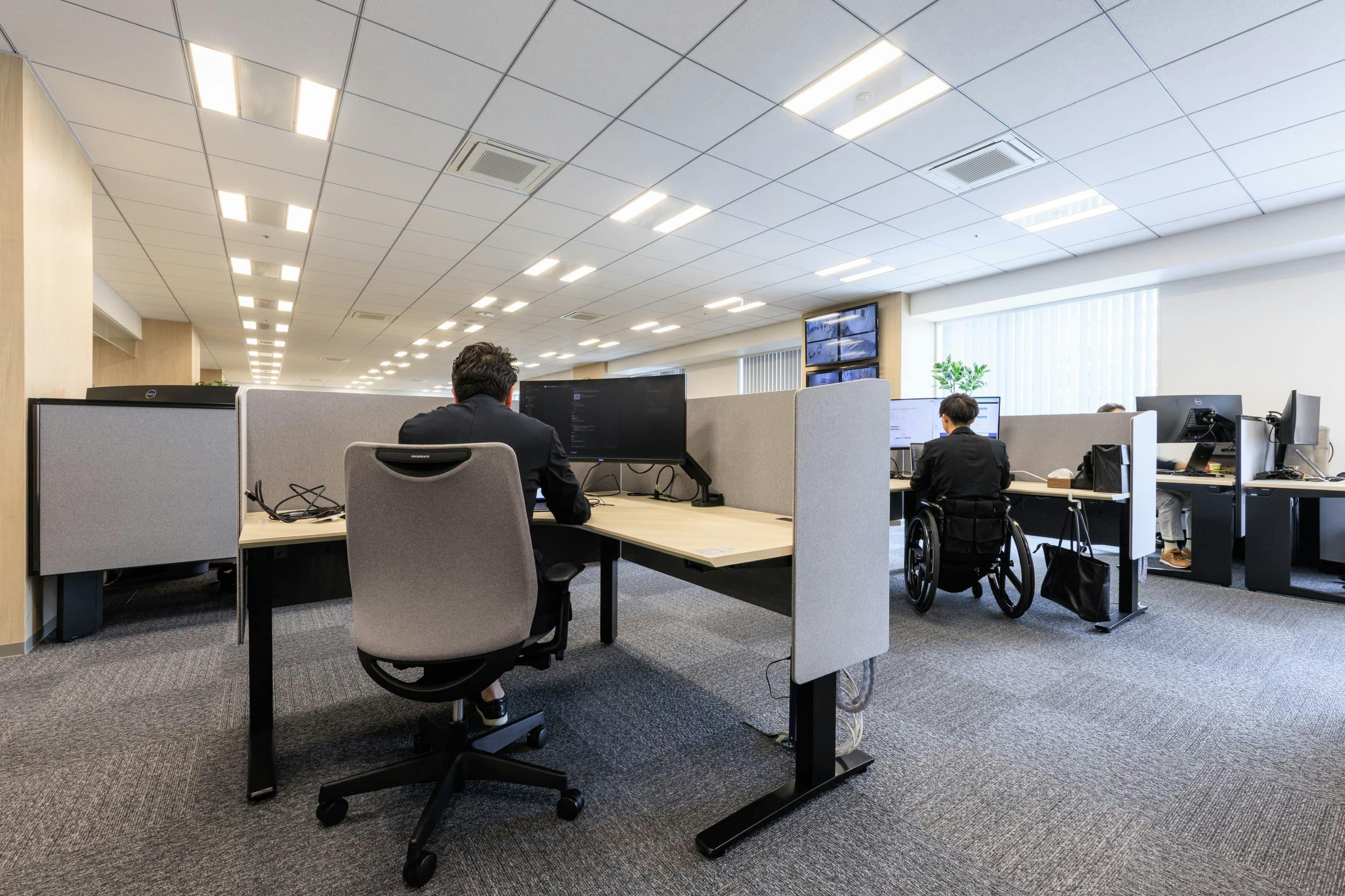 福井コンピュータホールディングス株式会社 様の事例写真／[13F フォーカスエリア]パネルに囲まれた電動昇降デスクは、周囲の視線が気にならず集中できます。動線が広いバリアフリー設計で車椅子を利用する従業員も働きやすいデザインになっています。