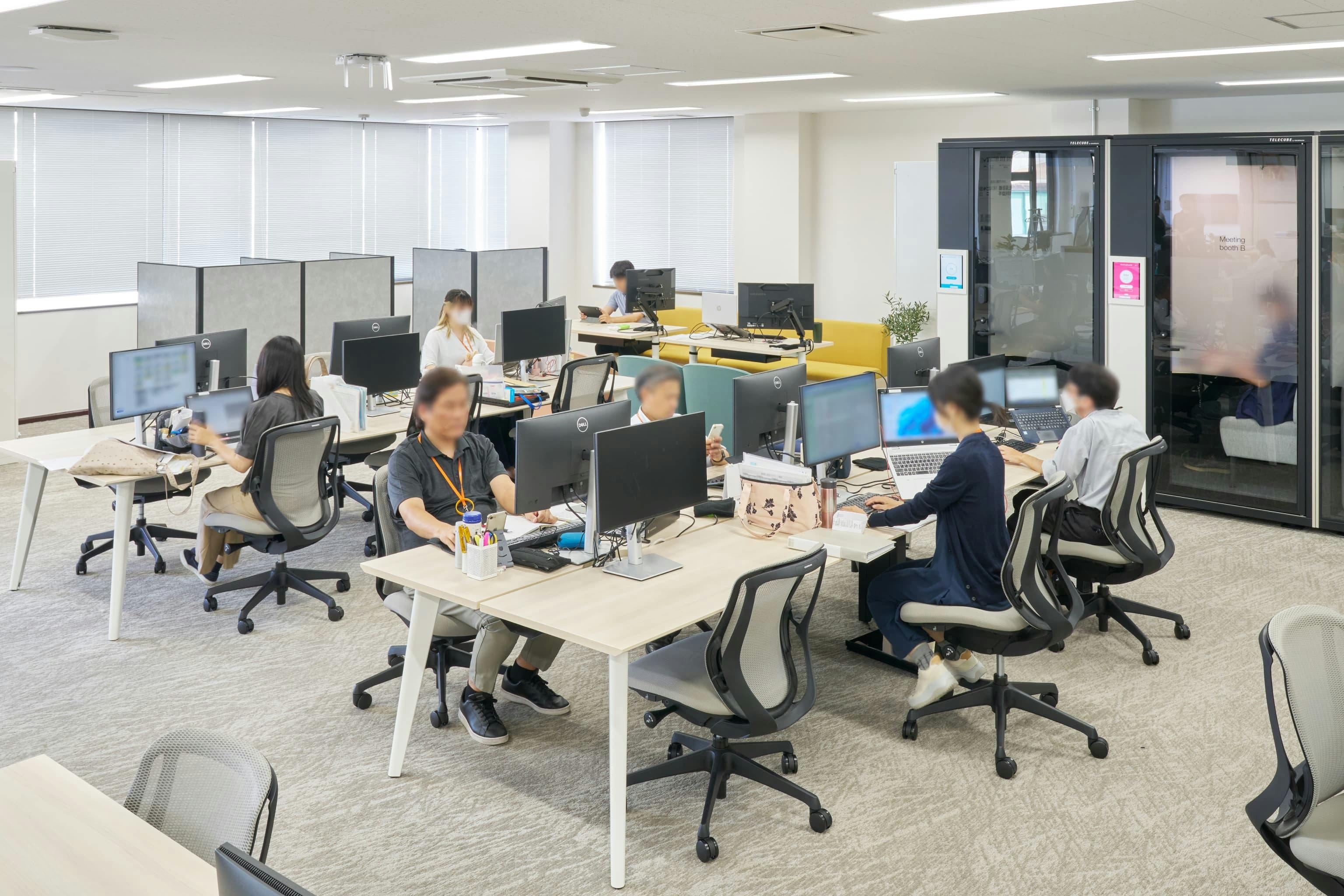 株式会社ウェルパーク 様の事例写真／[執務エリア]旧オフィスで親しまれていた島型レイアウトを継承しつつ、パネルで仕切られたブース席やモニター付きのソファ席などが設けられています。多様なワークスタイルに対応し、音や視線を気にせず集中できるエリアです。