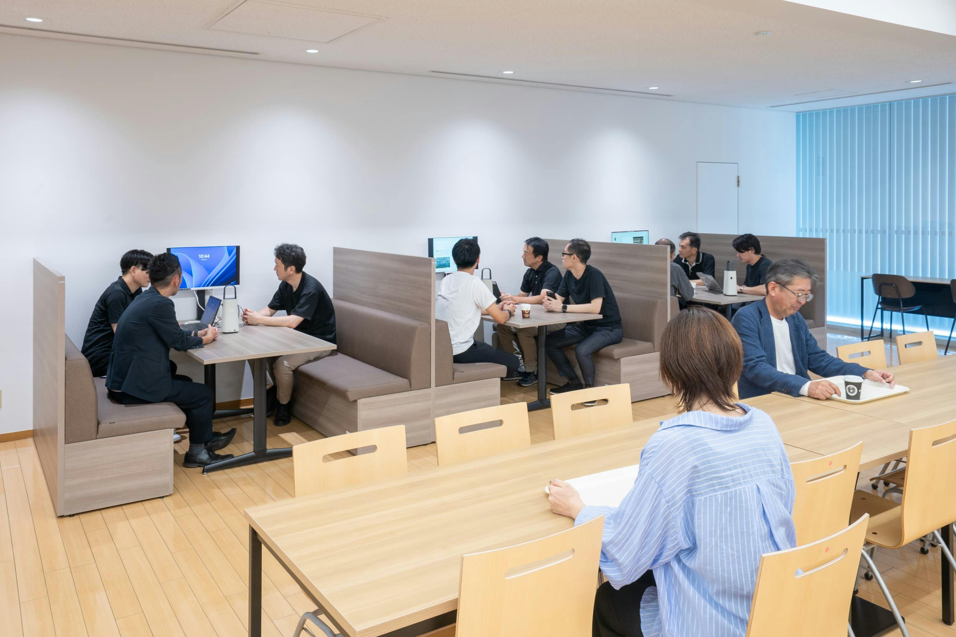 株式会社村田製作所 様の事例写真／[5階食堂]壁際のファミレスブースにはモニターが備え付けられ、業務時は打ち合わせスペースとして活用。会議室不足の解消に一役買っています。ソファの座面下には備品を収納することもできます。