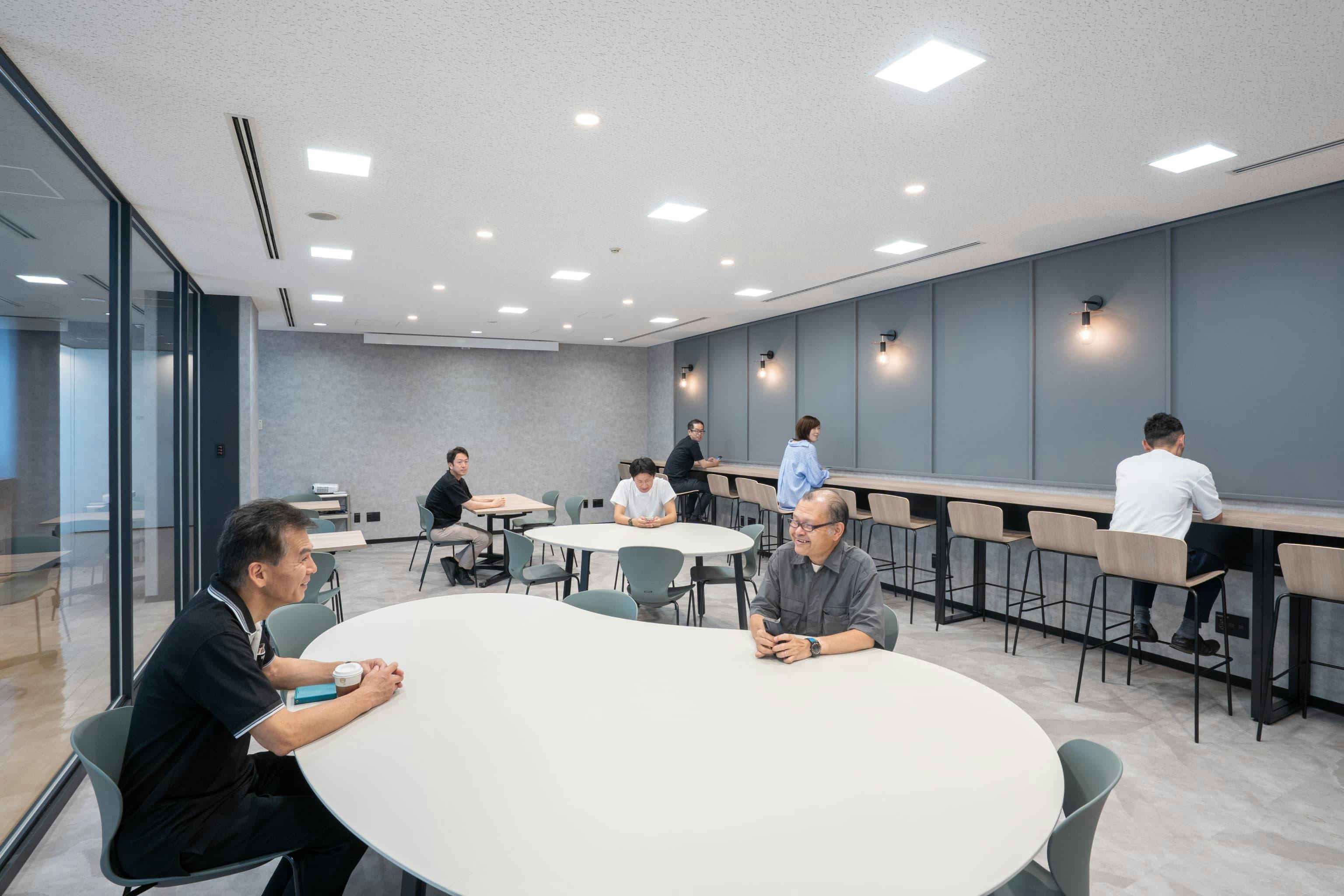 株式会社村田製作所 様の事例写真／[6階リフレッシュエリア]カフェの奥にある個室は、ガラスの間仕切りが採用され開放的な印象。什器は自由に移動できます。ロールスクリーンがあり、プロジェクターを利用した打ち合わせやイベントにも使えます。