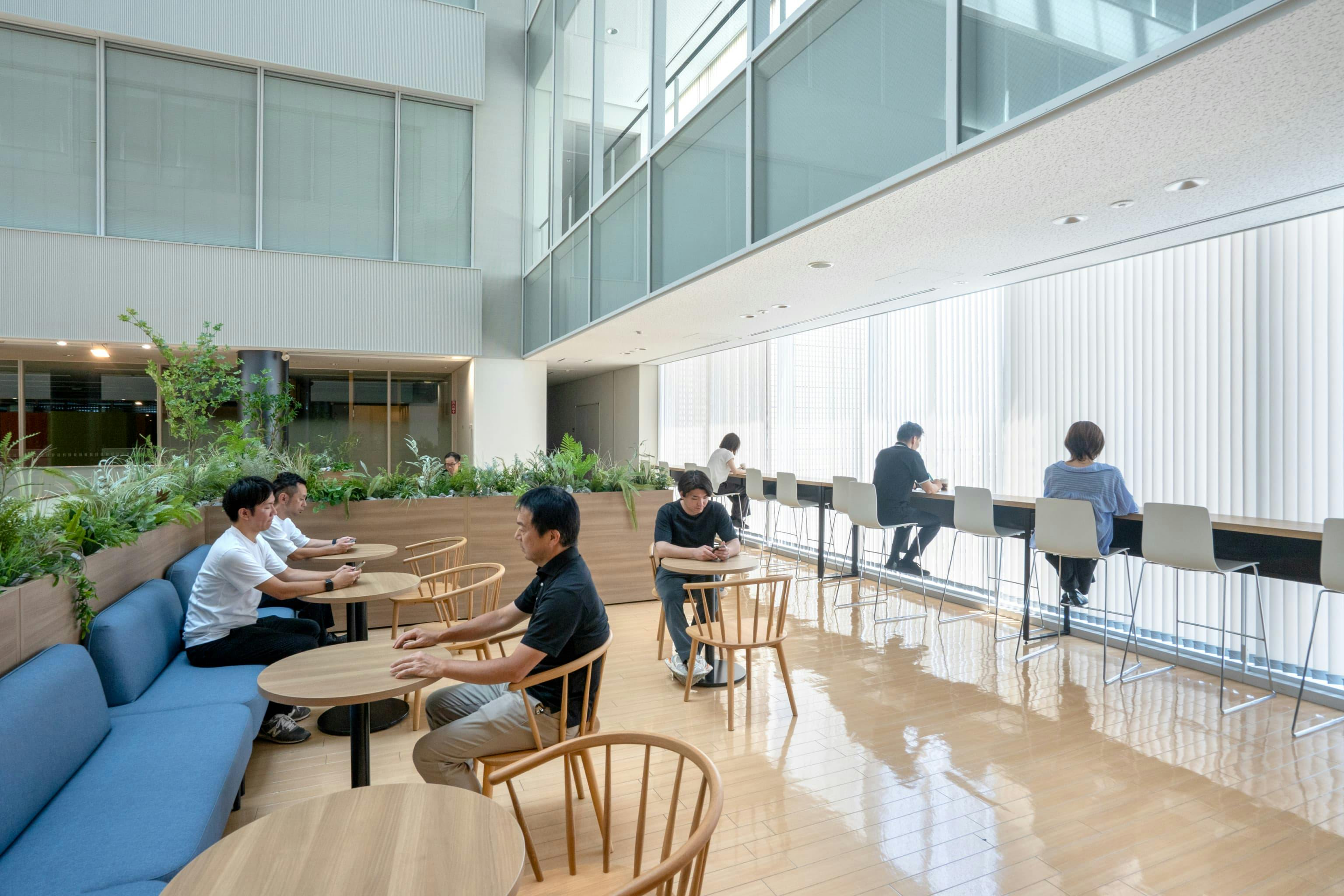 株式会社村田製作所 様の事例写真／[6階リフレッシュエリア]明るい自然光が降りそそぐ、アトリウムの一角。広い空間をあえて什器で仕切り、オープンでありながら落ち着ける工夫がされています。ソファの布地は、空間になじむブルーが採用されています。