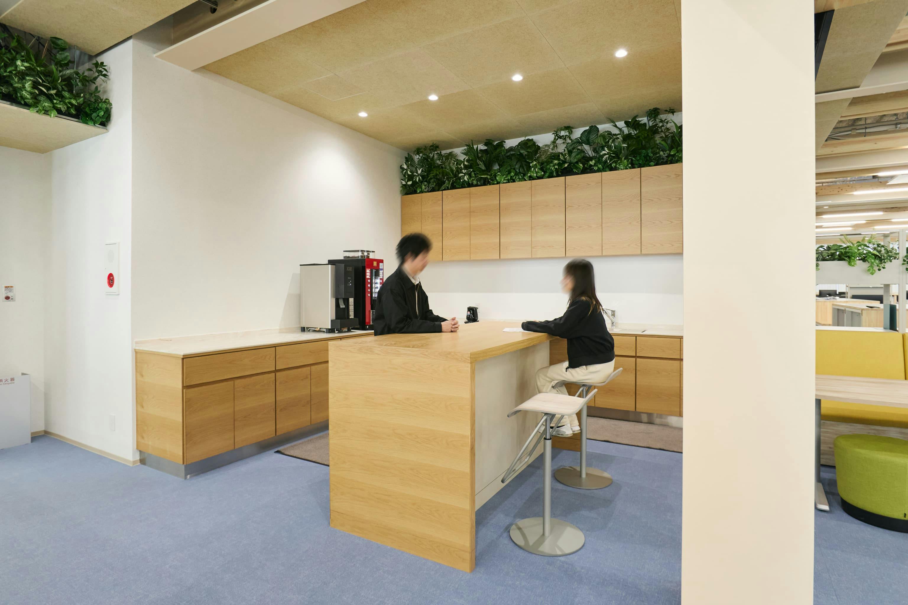 今治造船株式会社 様の事例写真／[1Fカフェコーナー（オフィス棟）]壁際の一角は、ほっと一息つけるカフェスペースです。ハイカウンター越しに立ち話をしたり、ハイスツールに座ってコーヒーを飲んだりと、リフレッシュタイムを過ごせます。