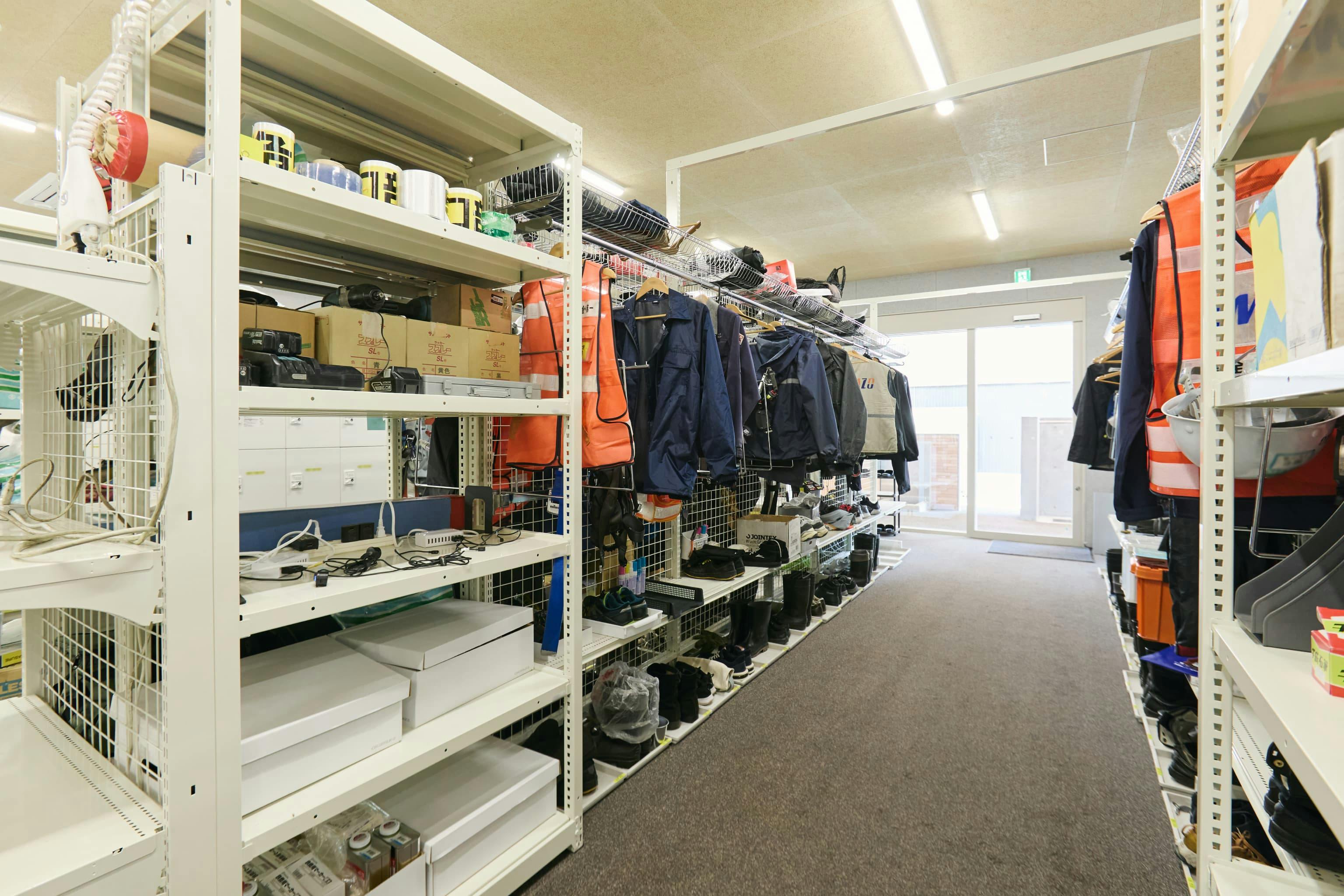 今治造船株式会社 様の事例写真／[1F装具置場（オフィス棟）]防寒服や作業服、作業靴、長靴、ヘルメットなどを収納する棚什器。既製品をカスタマイズし、装具によって棚の適切な高さや位置を調整しています。