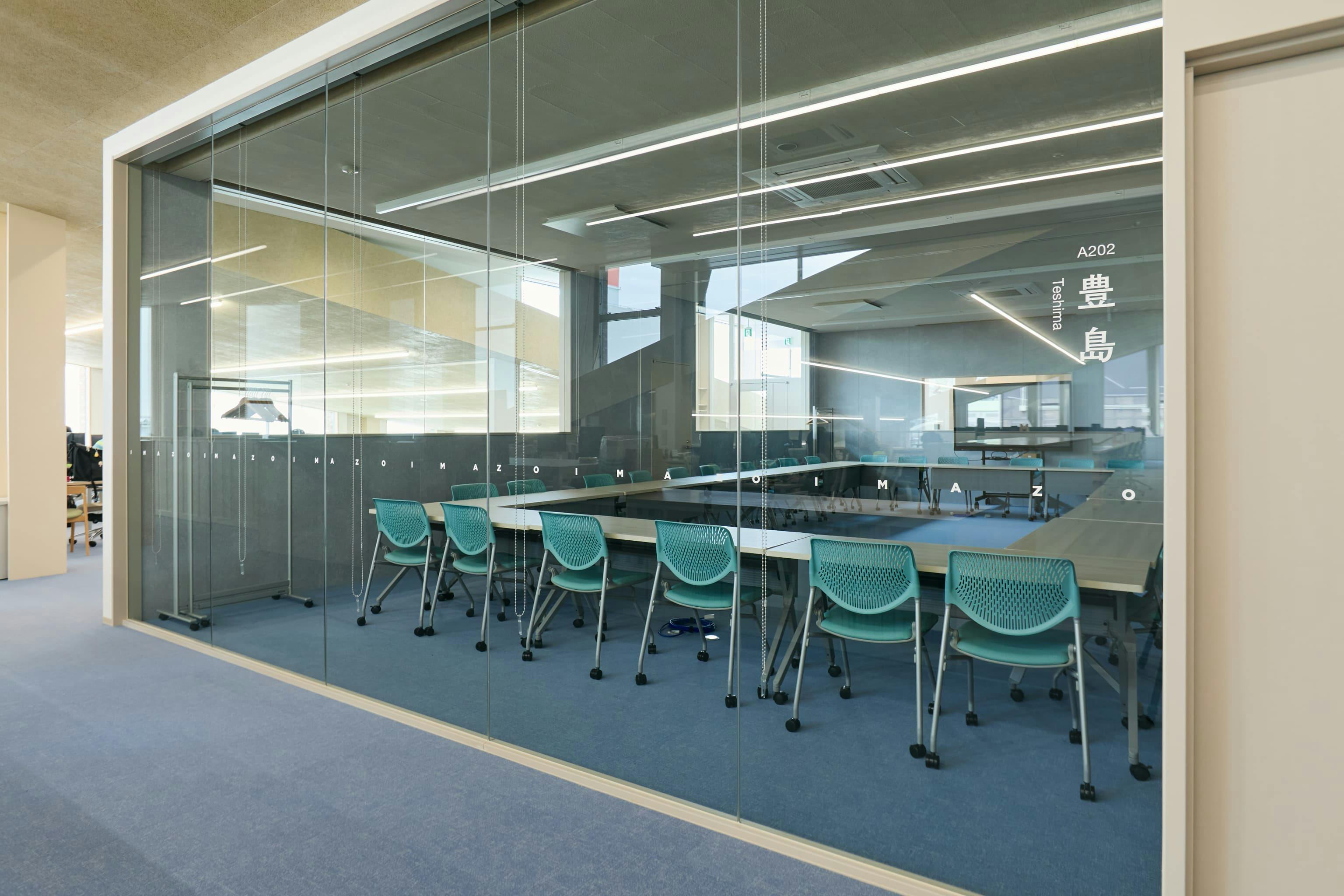 今治造船株式会社 様の事例写真／[2F中会議室（オフィス棟）]会議室にはそれぞれ、部屋の大きさによって瀬戸内海に浮かぶ離島の名前がつけられています。2階には会議室「豊島」「直島」が隣り合っており、可動式のパーティションを動かすことで1つの大部屋になります。