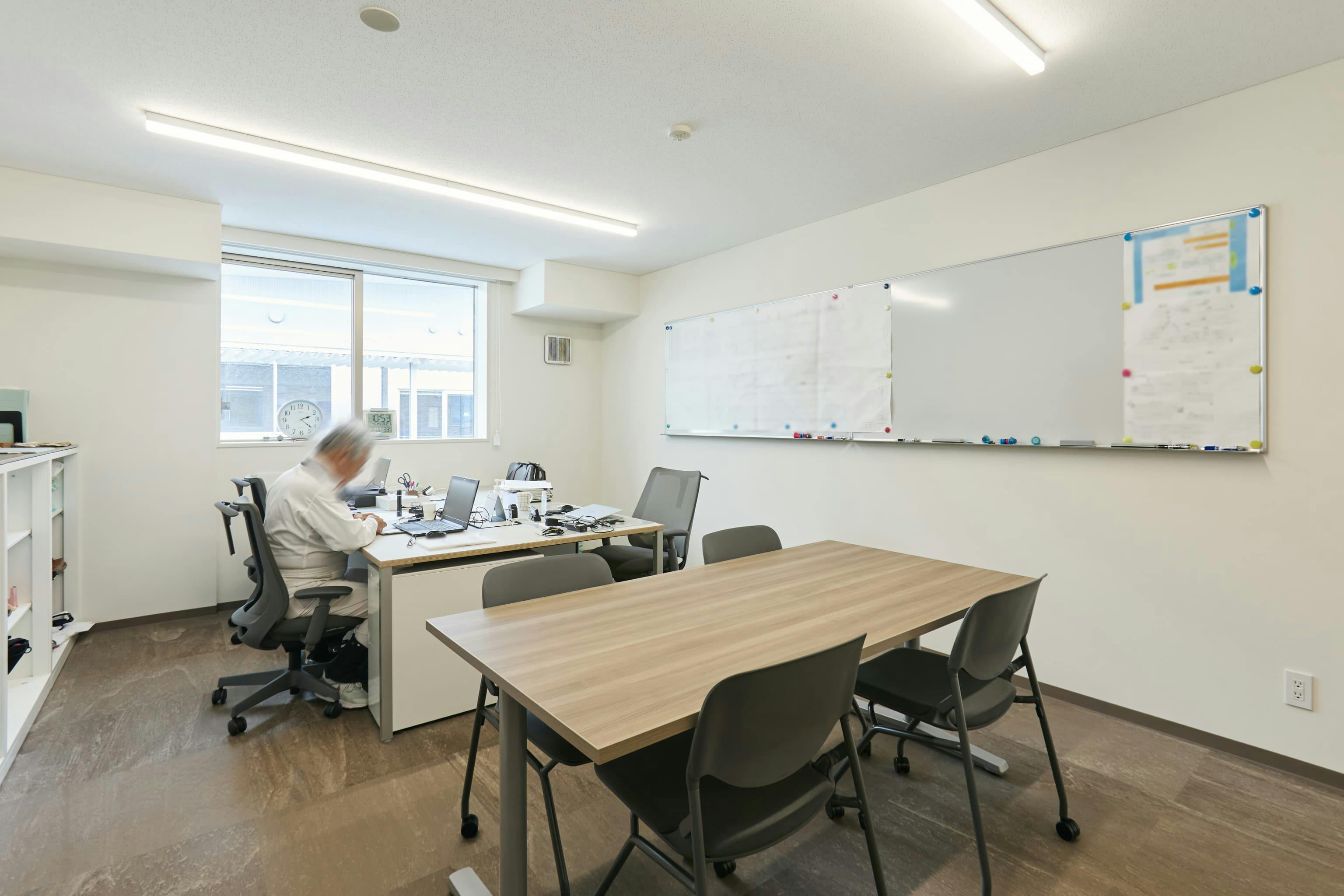 今治造船株式会社 様の事例写真／[2F監督員室（オフィス棟）]監督員室には、船の製造過程をチェックする監督員が常駐しています。製造現場の社員との打ち合わせが多いため、会議用テーブルとホワイトボードが備えられ、スムーズな情報共有を実現しています。