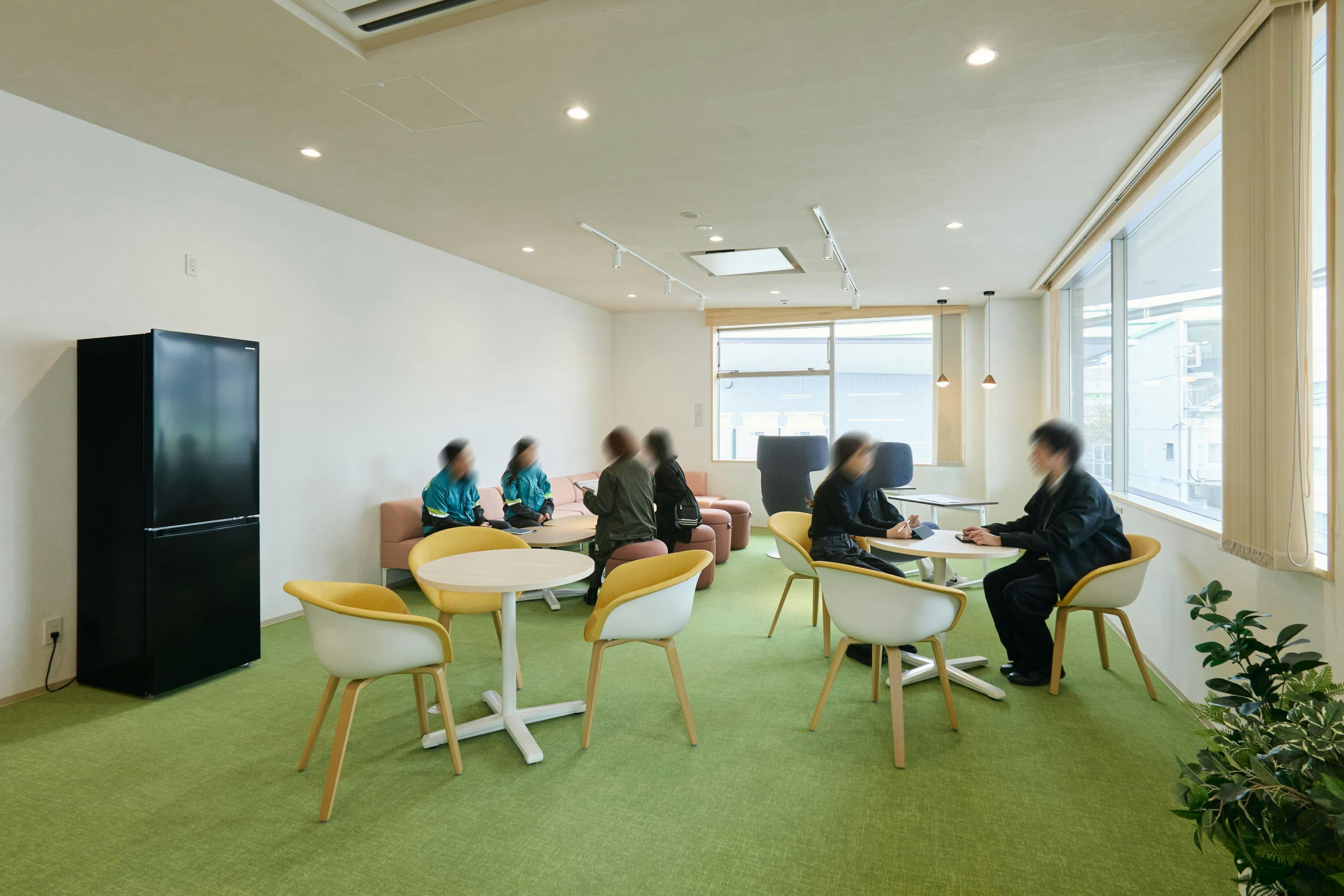 今治造船株式会社 様の事例写真／[2Fリラクゼーションルーム（オフィス棟）]冷蔵庫やコーヒーサーバーを備え、息抜きスポットとして利用されています。穏やかなトーンのピンク色や黄色の什器が置かれ、落ち着きがありつつも楽しげな印象です。