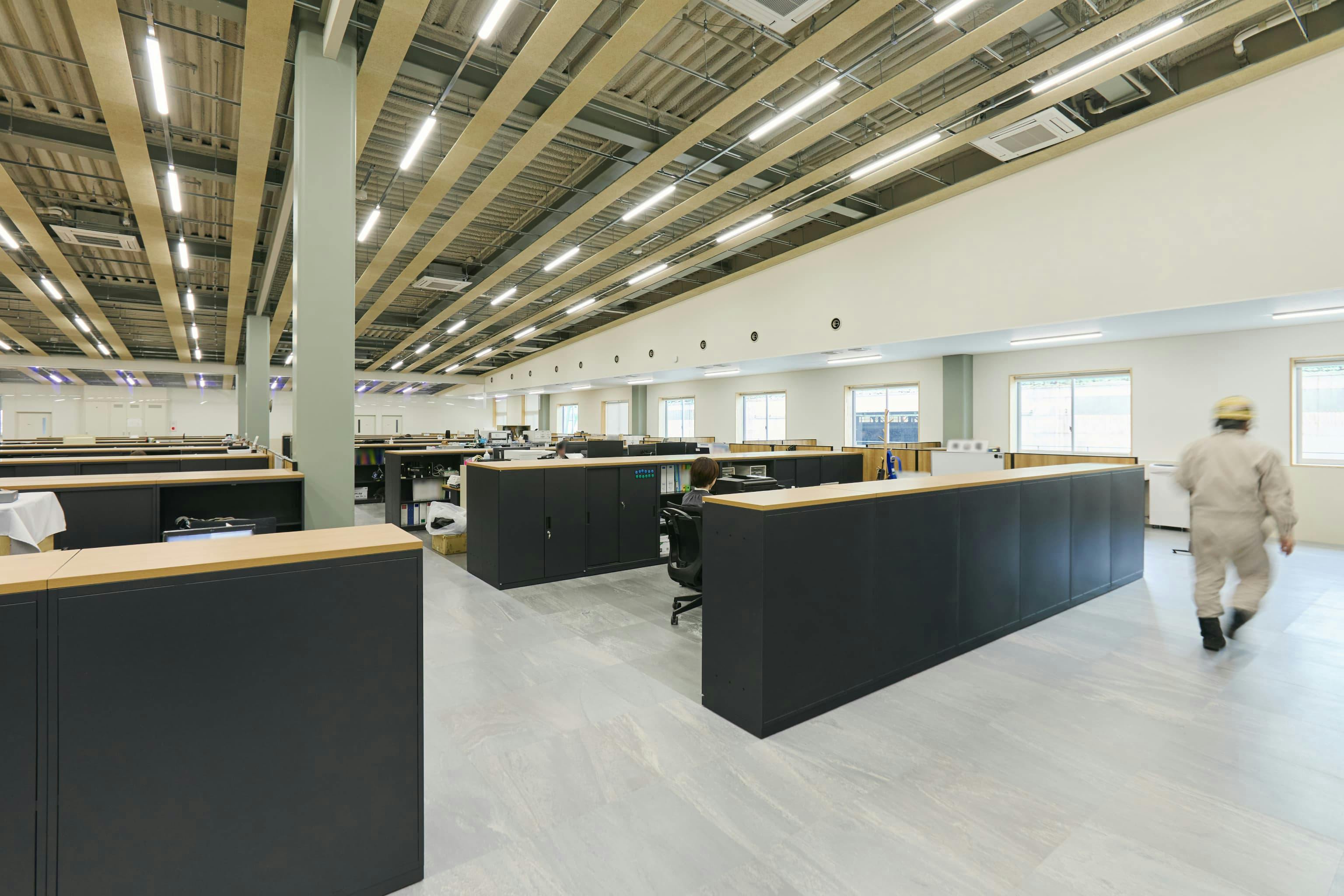 今治造船株式会社 様の事例写真／[2F協力会社オフィス（ラウンジ棟）]食堂の上階には、協力会社が入居する執務フロアがあります。視線が抜ける設計と落ち着いたトーンが、静かに集中できる環境とコミュニケーションの取りやすさを両立させています。