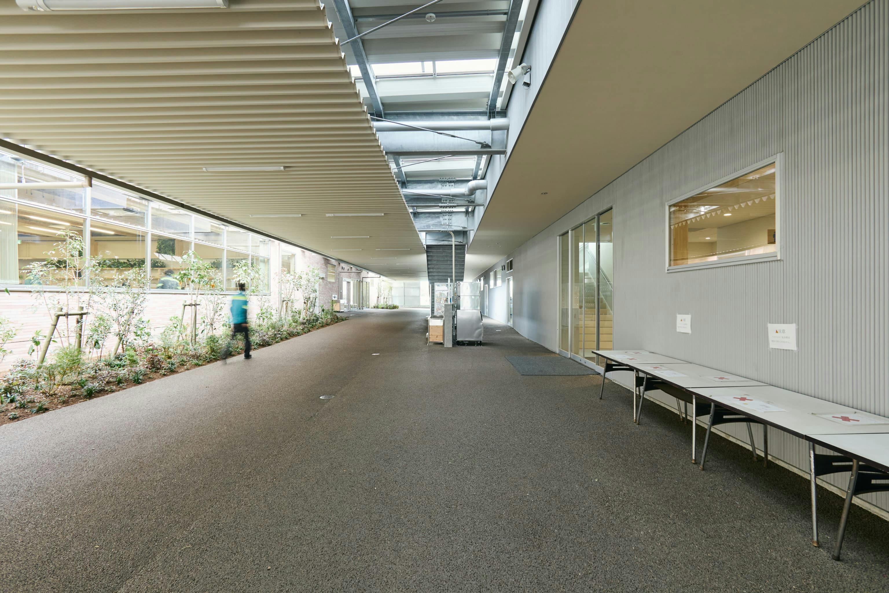 今治造船株式会社 様の事例写真／[通路]オフィス棟（写真左）に隣接するラウンジ棟（写真右）。雨天時もスムーズに行き来でき、休憩時間に多くの人が行き交ってもゆとりのある広めの通路が確保されています。