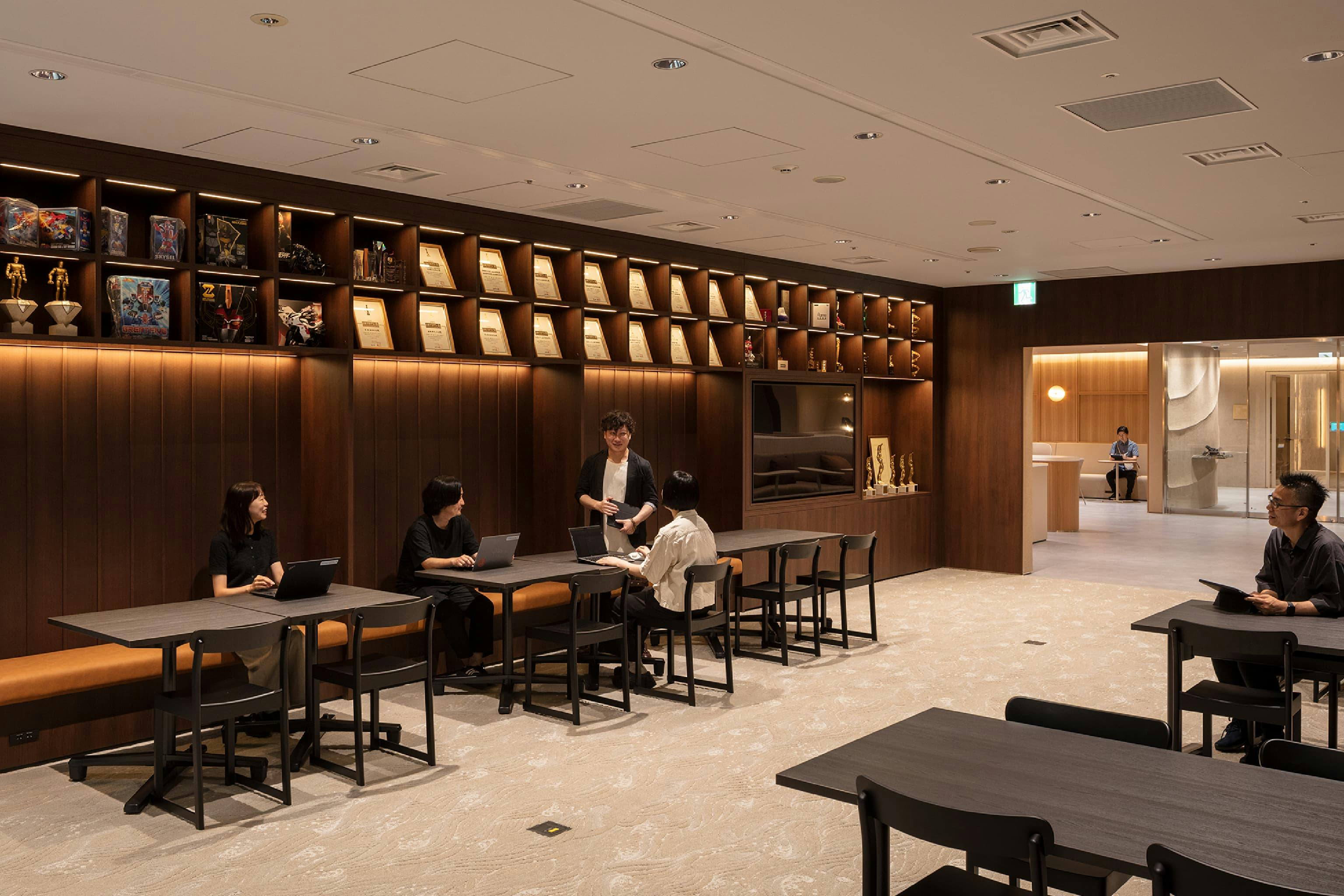 東映株式会社 様の事例写真／[9階 待合エリア]試写会の上映前の時間を過ごす待ち合いスペースは落ち着いた色調で、映画館のロビーを思わせます。壁面の飾り棚に並ぶトロフィーや賞状が東映配給作品の功績を伝え、これから上映される作品の期待感をより高めてくれます。
