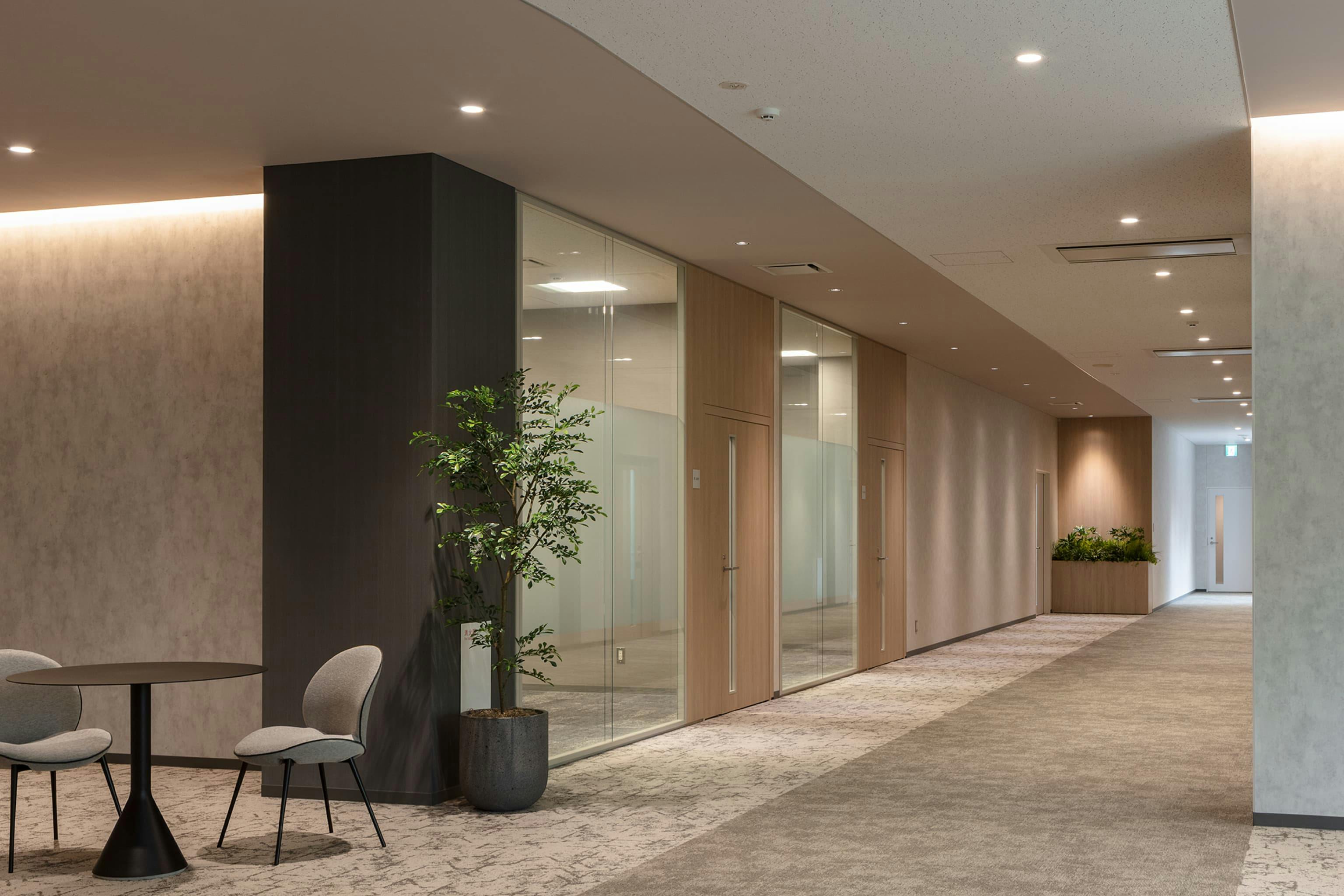 第一法規株式会社 様の事例写真／[1F役員フロア]役員室に続く通路は、温かみと重厚感のある色合いで統一されています。スポット照明やライン照明がもたらす陰影が、特別な空間を演出しています。
