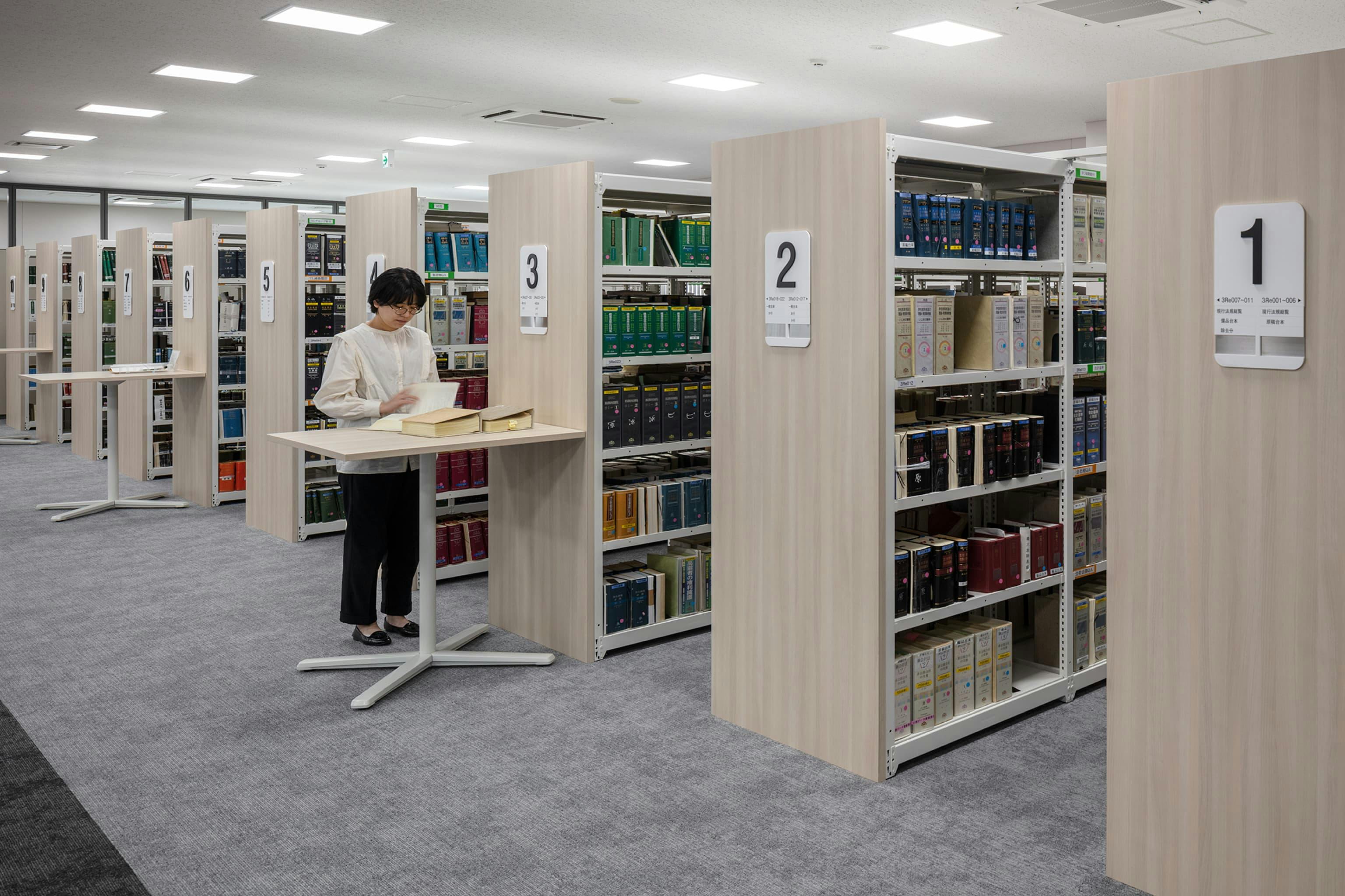 第一法規株式会社 様の事例写真／[3F執務フロア（編集用資料エリア）]自社の出版物を収納している編集用資料エリア。棚ごとに本のジャンルが分類されていて、必要な資料をすぐに見つけられます。