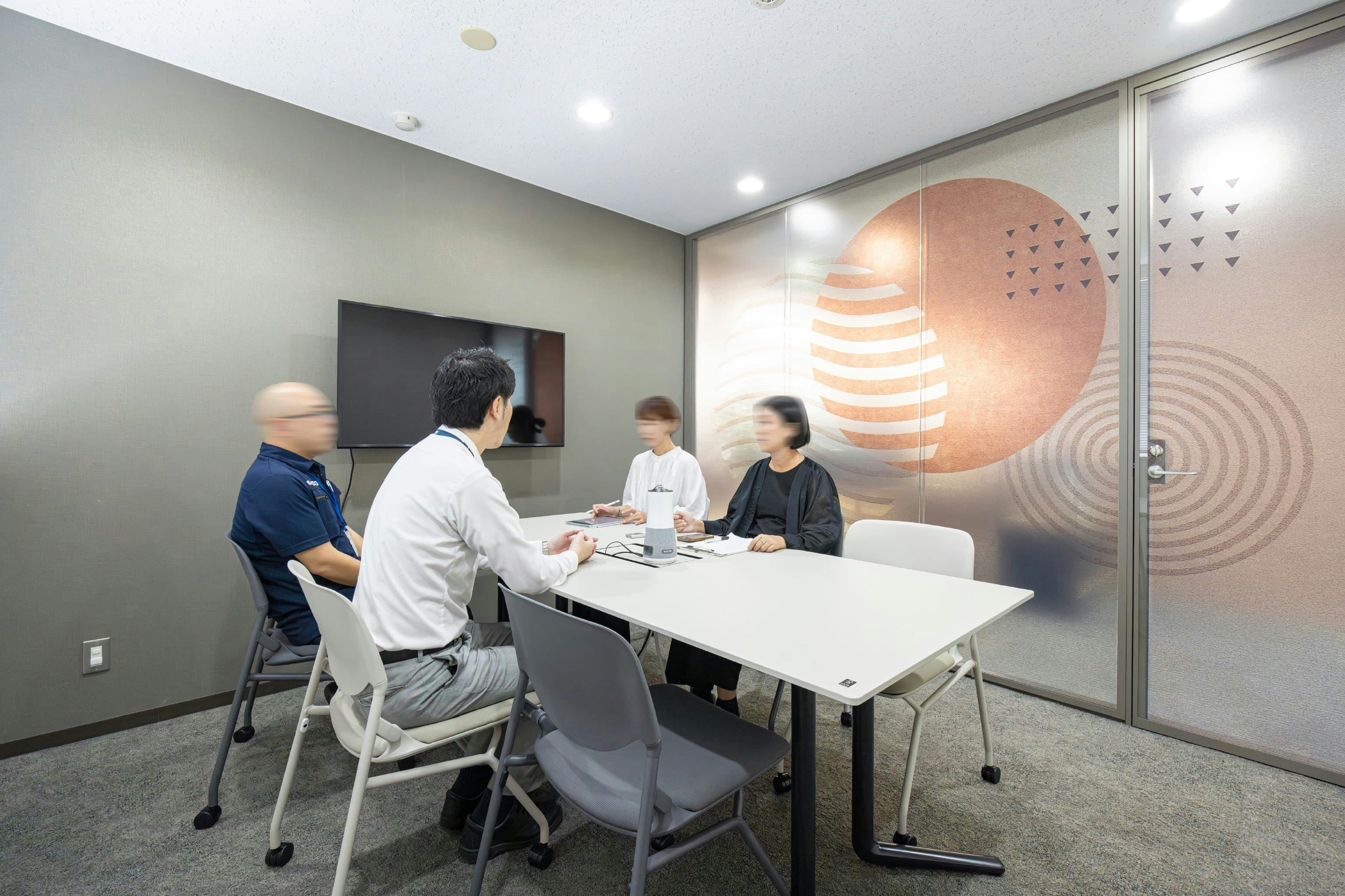 日本ガスケット株式会社 様の事例写真／[応接室]エントランス横の応接室は、来訪者をスムーズに案内できます。来客対応のほか、社内の打ち合せで活用することも。ガラス壁で開放感を出しつつ、ほどよく目隠しになるシートを貼ってプライバシーにも配慮されています。