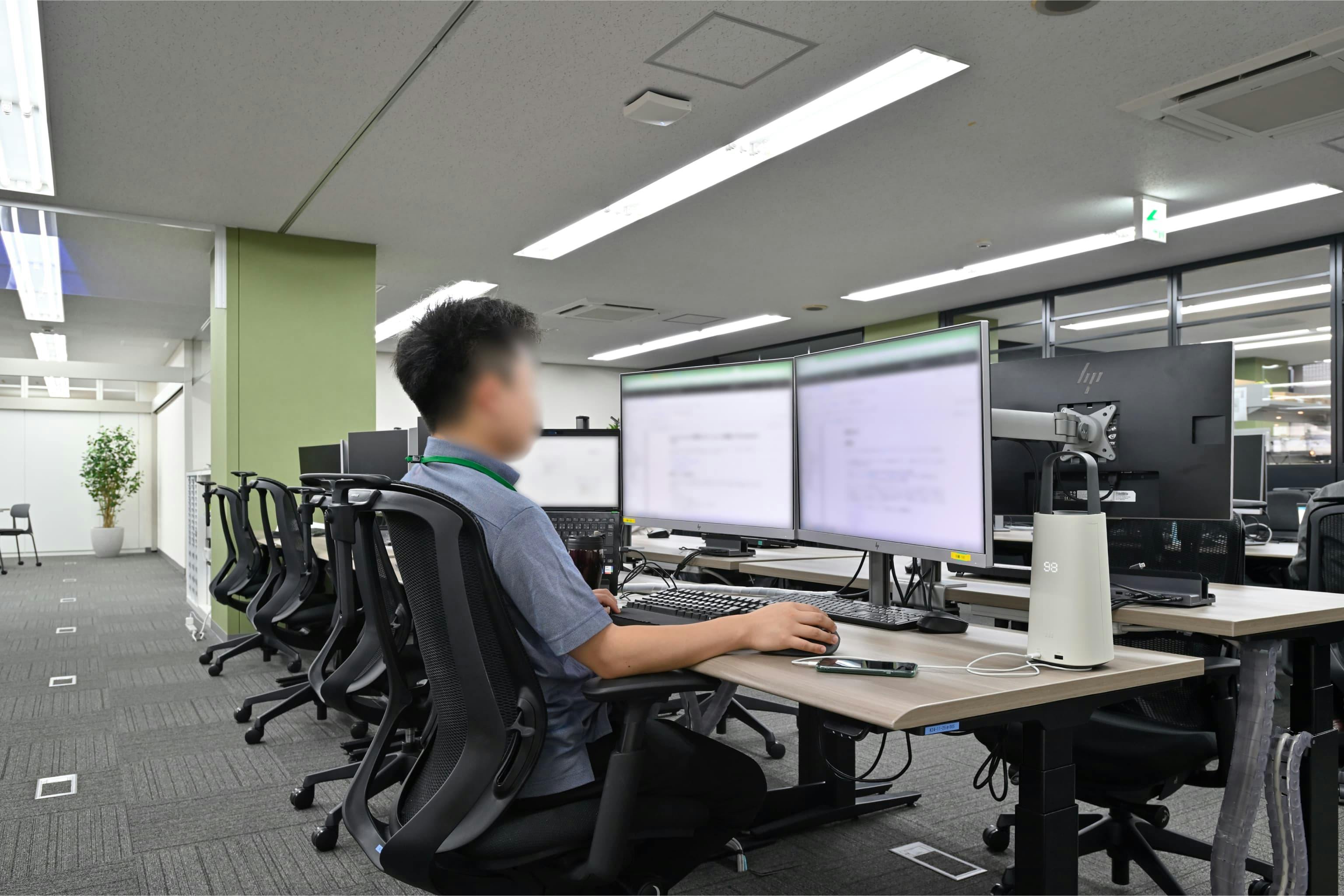 株式会社エスケイケイ 様の事例写真／[執務エリア]広めの天板はデュアルモニターとOCポータブルバッテリーを置いても余裕があり、手元の作業スペースも十分です。電動昇降デスクは座り姿勢でも、目線や作業姿勢に合った高さに調整でき、快適に作業を進められます。