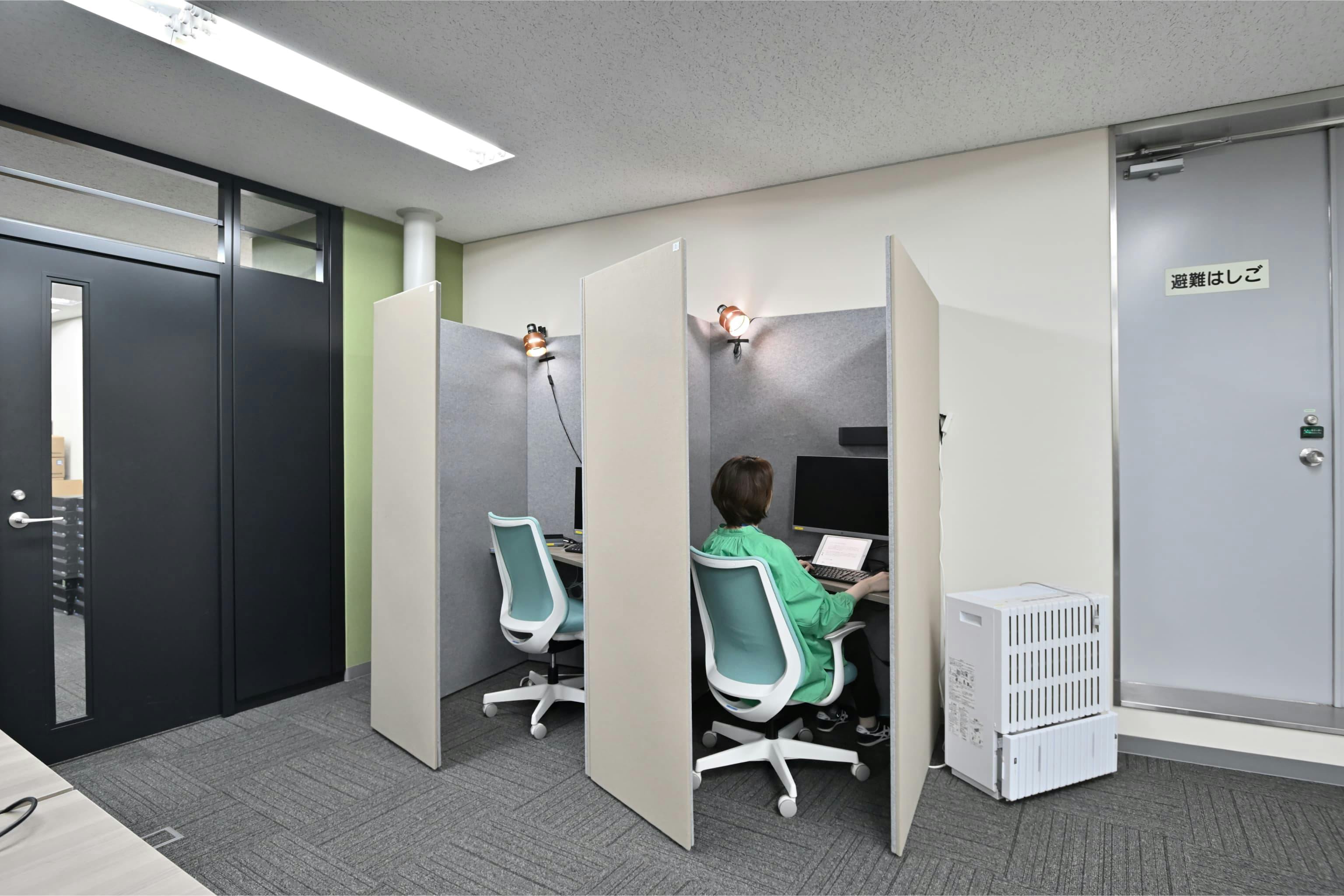 株式会社エスケイケイ 様の事例写真／[執務エリア]吸音パネルで囲われたソロワークブースは、1〜2時間ほど集中したいときに便利。没頭できると好評で、利用率が高いスペースです。ライトブルーの椅子が、ベーシックトーンの執務エリアの軽やかなアクセントに。