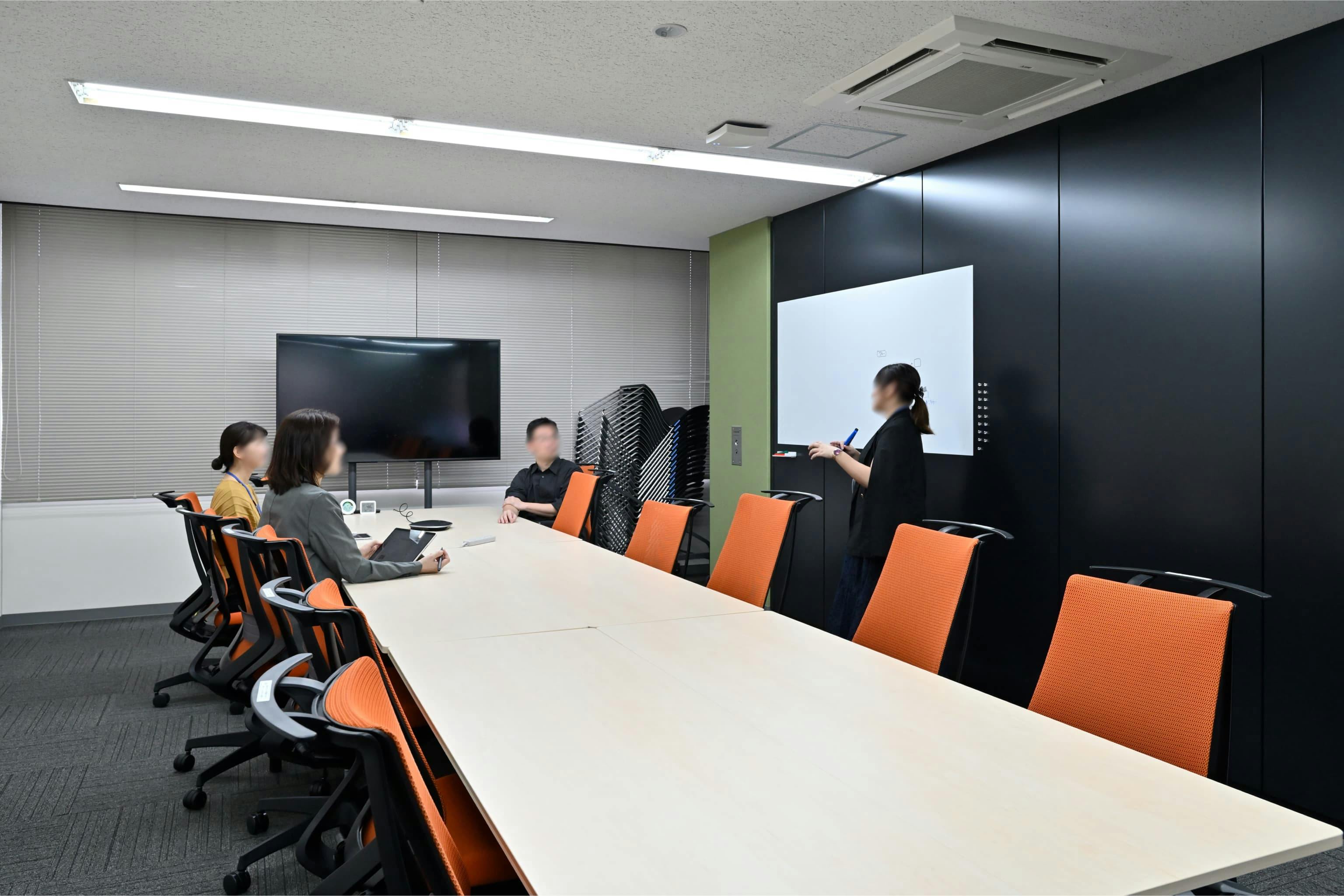 株式会社エスケイケイ 様の事例写真／[会議室]個室の会議室は、より集中して議論したいときに利用されます。壁にはホワイトボードシートが貼られており、書き込みながらディスカッションが可能。外部とのオンライン会議など、音が気になるシーンでも活用されています。