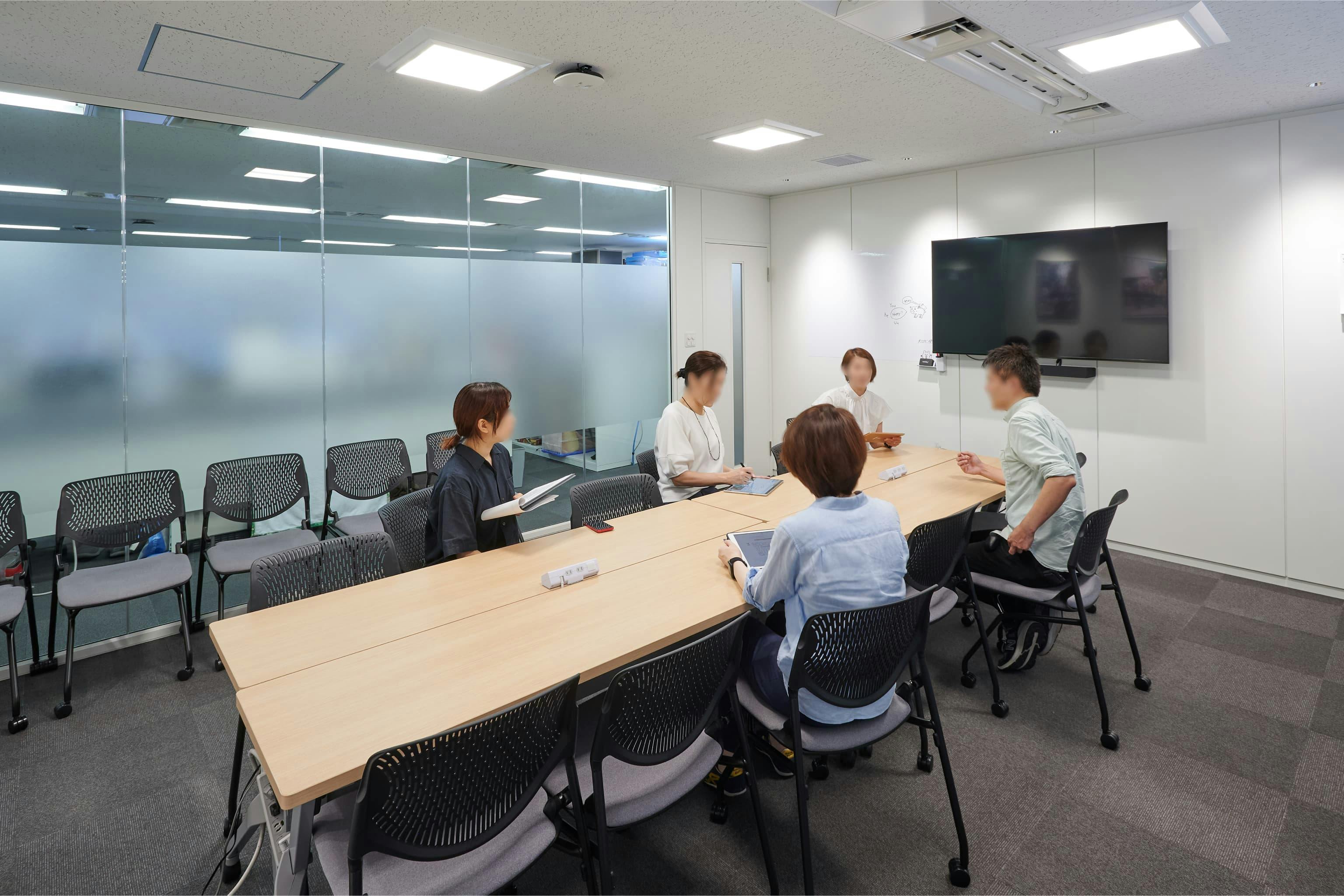 株式会社A-1 Pictures 様の事例写真／[N棟3F会議室]脚本会議などにも使われる、大型モニター付きの大会議室。可動性のあるチェアで、人数や用途に応じた柔軟なレイアウトが可能です。ガラス面は光を取り込みつつ目隠しで視線をやわらげ、室内のプライバシーにも配慮されています。 