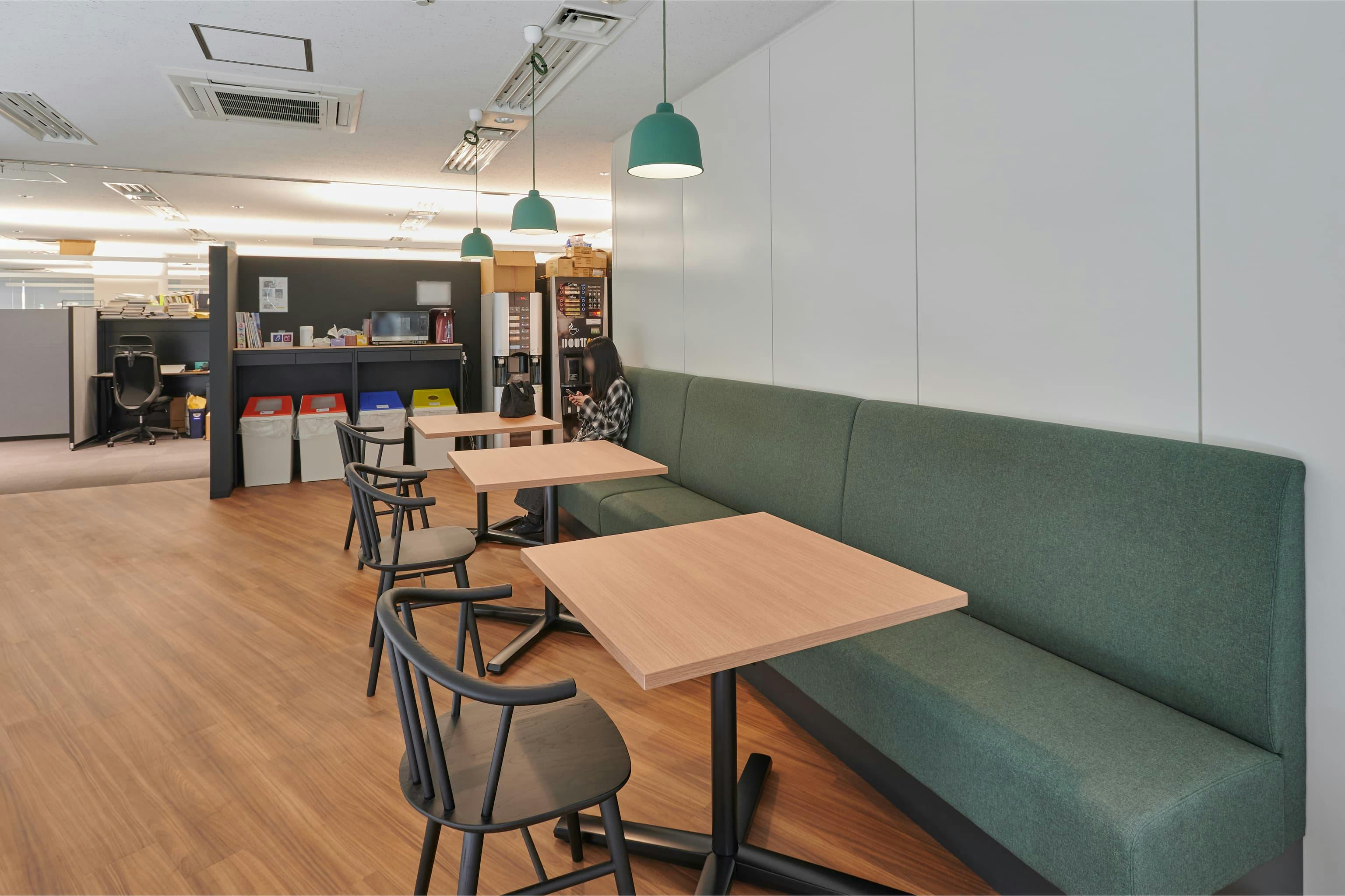 株式会社A-1 Pictures 様の事例写真／[S棟3Fリフレッシュスペース]三角形のフロア形状を活かし、作業席を設けにくい空間をリフレッシュスペースとして活用。造作ソファを採用し、デッドスペースを生まない設計に。穏やかなグリーンを向かい合う黒のチェアが引き締め、落ち着ける雰囲気です。