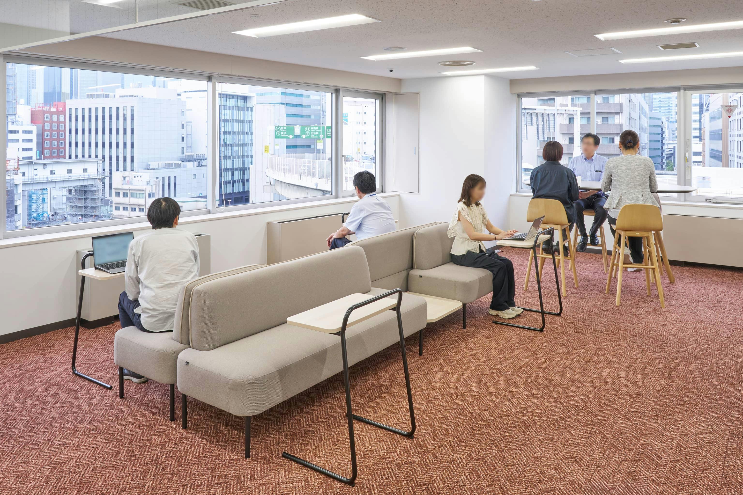 ジェイエスフィット株式会社 様の事例写真／[6F ABWエリア]暖色のカーペットと丸みのあるソファで、やわらかな雰囲気が広がります。休憩はもちろん、ノートPCを置けるミニテーブルも備えられ、作業や打ち合わせにも。ひと息ついて、気分を切り替えられるスペースです。