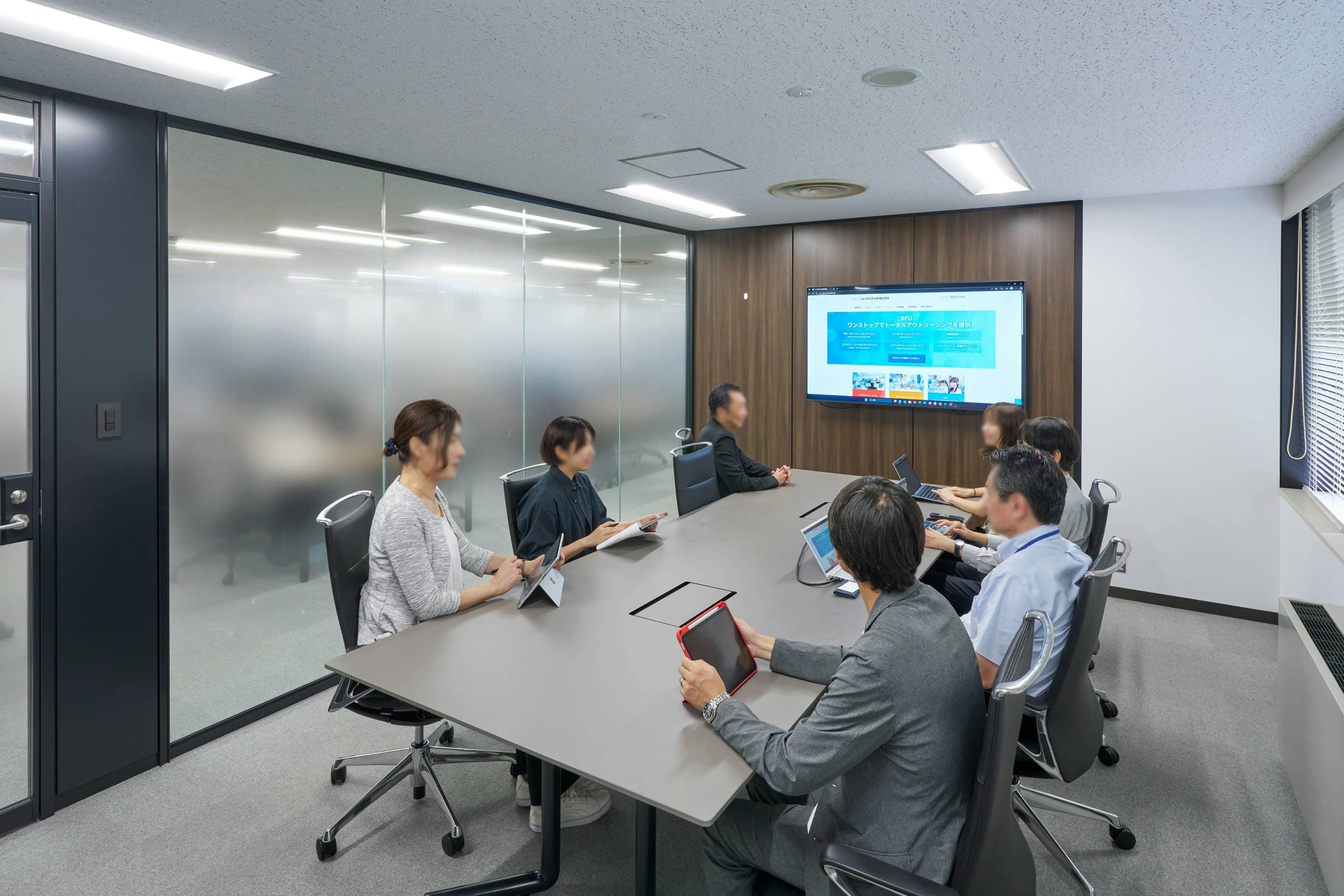 ジェイエスフィット株式会社 様の事例写真／[8F会議室]ガラス面のグラデーション加工により、プライバシーを守りつつもオープンな印象です。外から会議室の利用状況がわかるため、使いやすさにも配慮されています。上質感のあるチェアが並び、落ち着いた雰囲気です。