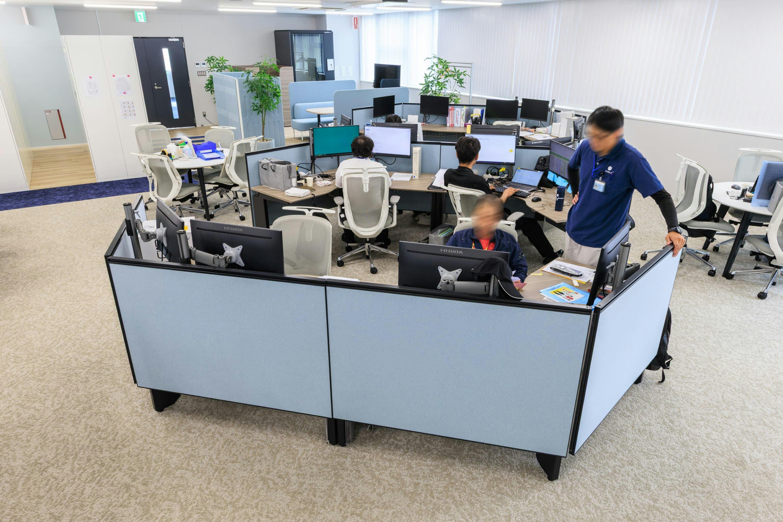 エア・ウォーター・エンジニアリング株式会社 様の事例写真／[3F執務エリア]パネルで囲まれたデスク島は、視線がほどよく遮られ集中できます。角度がついた幅広なデスクはデュアルモニターで作業しやすく人気の席。隣に立ったり椅子を持ってきたりして、同じ画面を見ながら気軽に話せます。