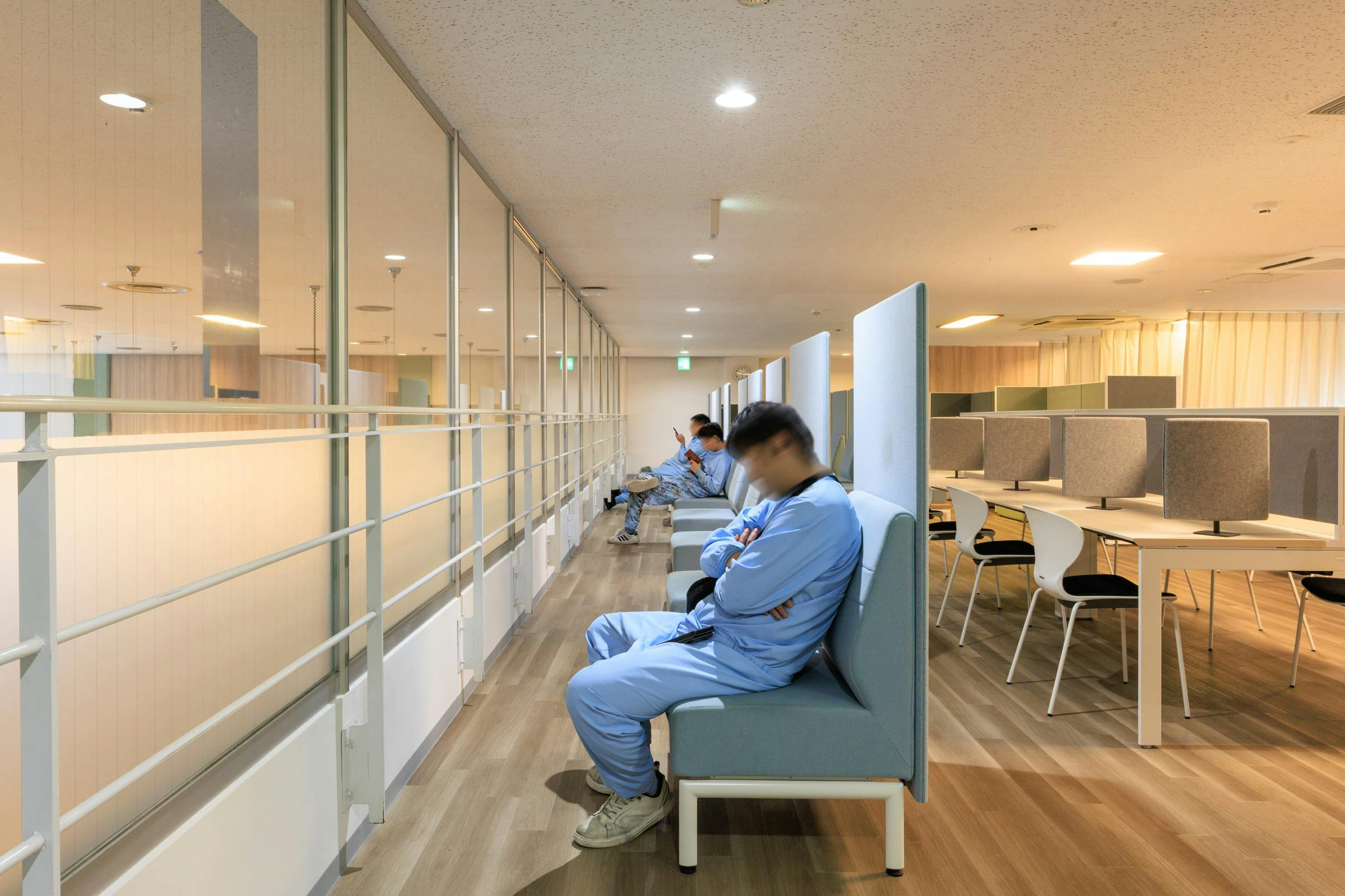 TOPPAN株式会社 ／ TOPPANパッケージプロダクツ株式会社 様の事例写真／[食堂上休憩エリア 一人掛けソファ席]適度なクッション性がある一人掛けのソファは、座り心地の良さを重視して選ばれたもの。1階の食堂から休憩エリアが丸見えになるのを防ぐため、ガラス面の一部に目隠しを施しています。