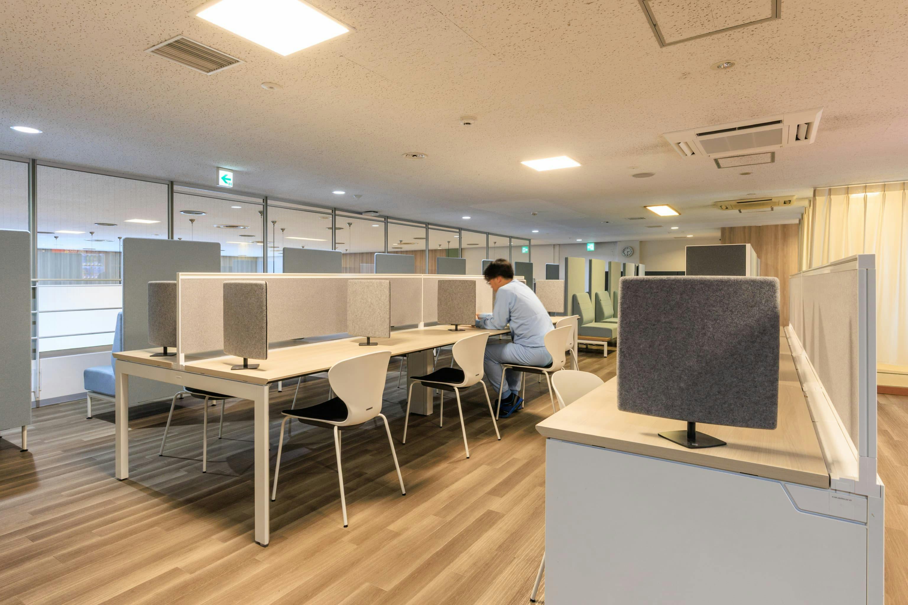 TOPPAN株式会社 ／ TOPPANパッケージプロダクツ株式会社 様の事例写真／[食堂上休憩エリア パネル付きテーブル席]一人で静かに利用しやすい、パネル付きのテーブルとチェア。自動販売機で買ったドリンクを飲んだり、スマートフォンをチェックしたりと、ちょっとした息抜きに使われています。