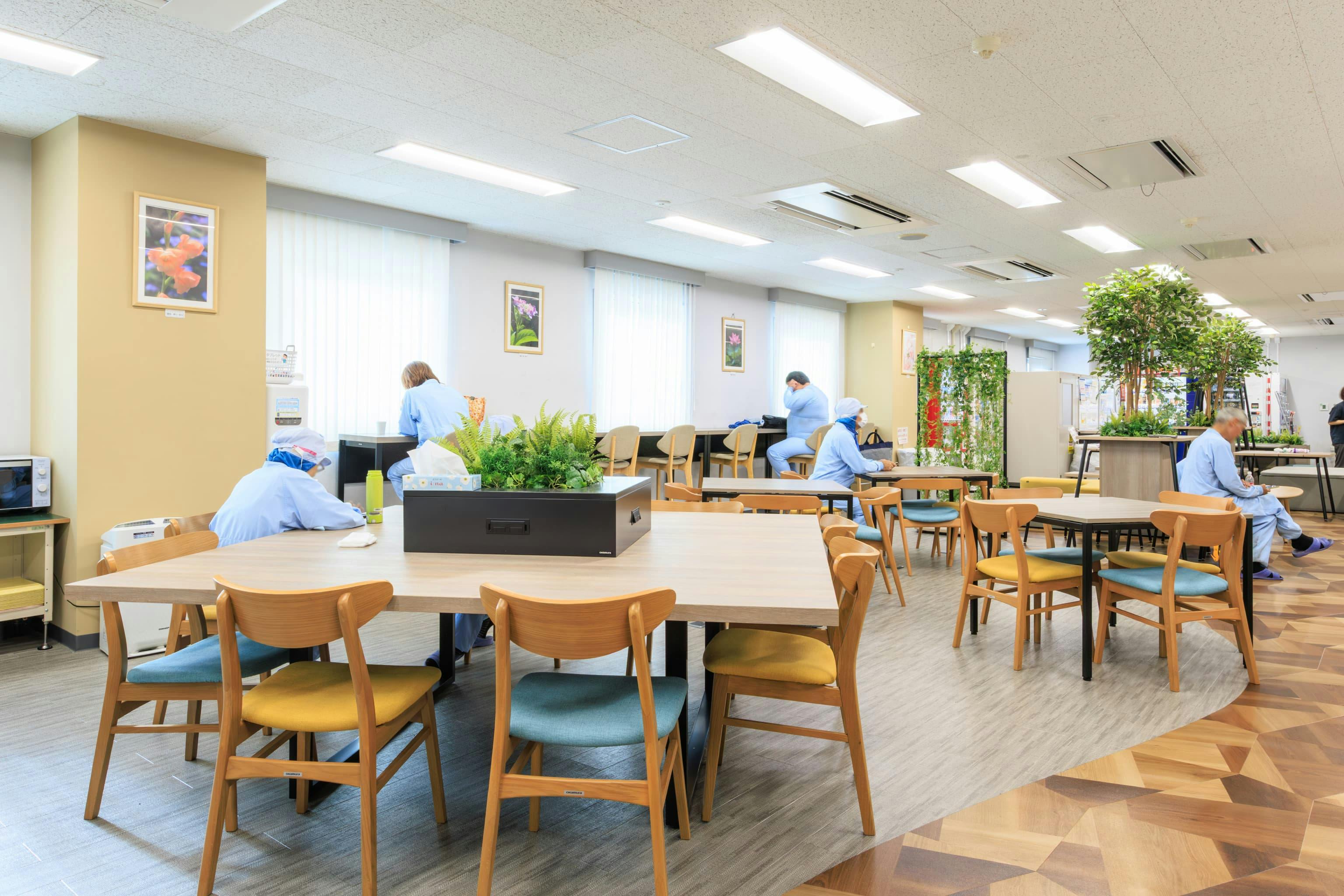 TOPPAN株式会社 ／ TOPPANパッケージプロダクツ株式会社 様の事例写真／[休憩エリア 大型テーブル席]中央の大型テーブルは席間隔にゆとりがあり、相席しやすい雰囲気です。「おつかれさま」と声をかけて座ると、ほどよい距離感で自然と会話が生まれていきます。