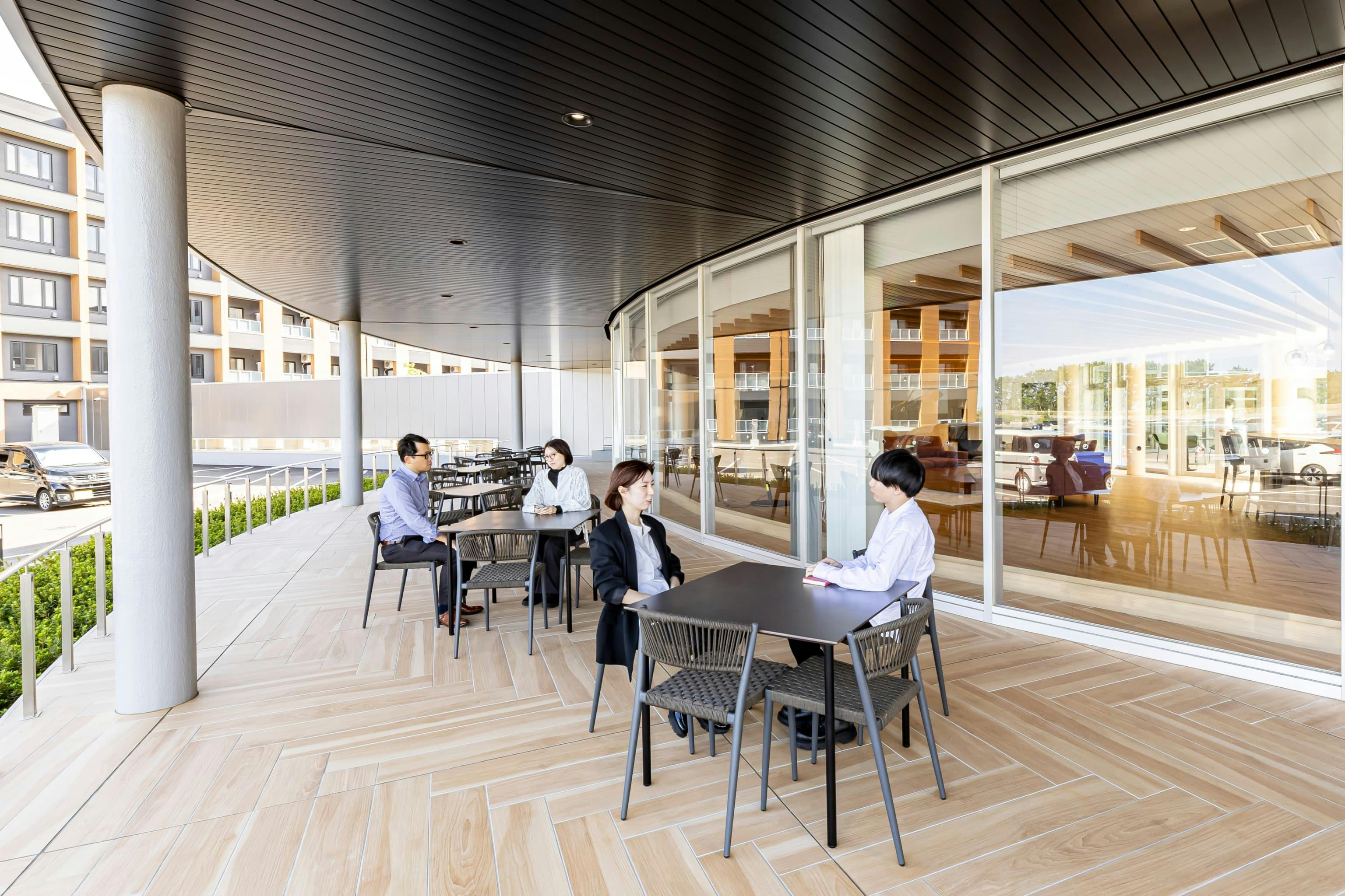 日産自動車九州株式会社 様の事例写真／[共用棟 1F テラス]近くに海岸があるため、潮風を感じられるテラスは、バーベキューなど社内イベントにも活用されます。社員同士がカジュアルな雰囲気で交流できる場に。準備や後片付けをしやすいよう水回りの設備が併設されています。