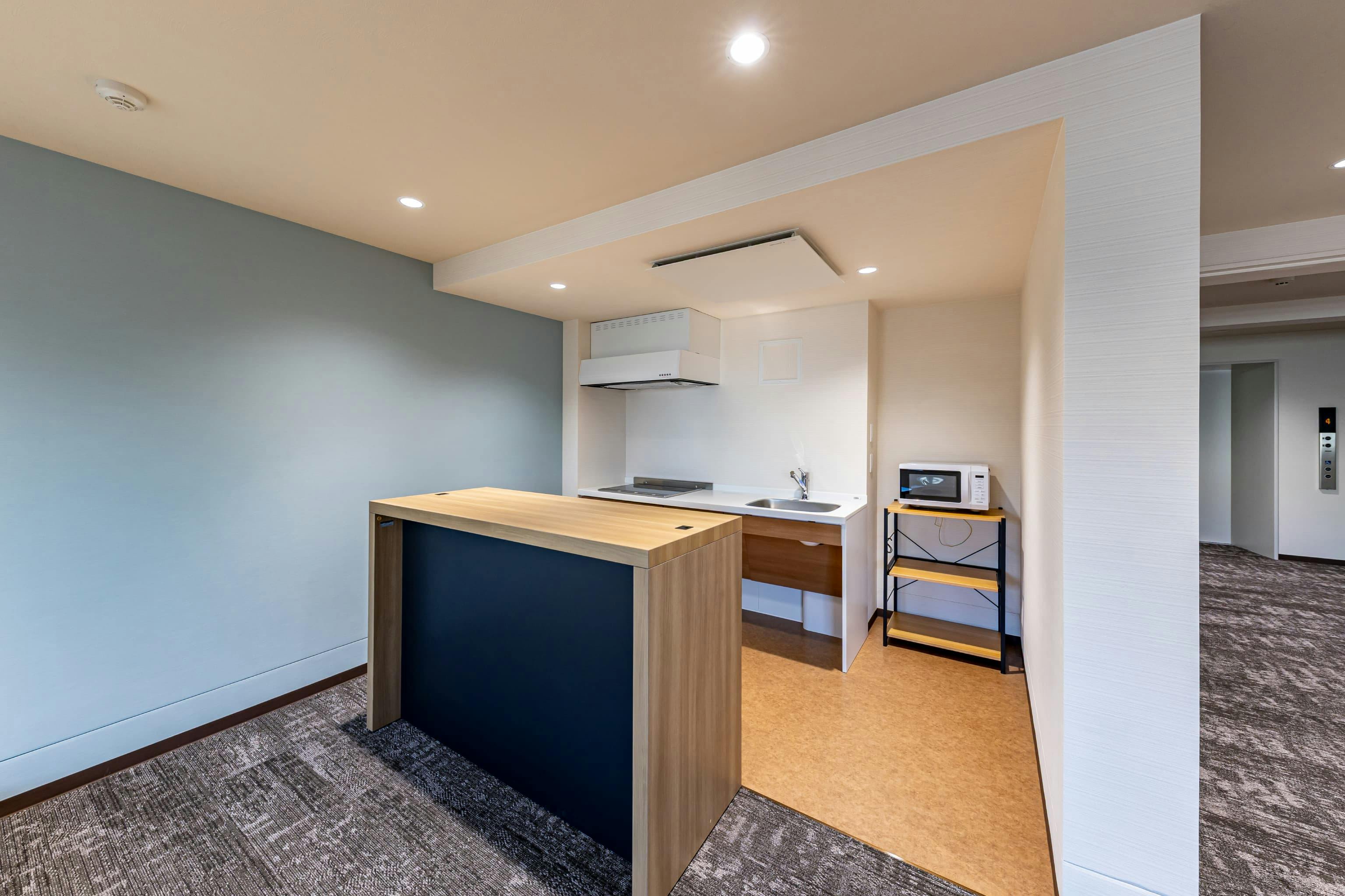 日産自動車九州株式会社 様の事例写真／[ドミトリー棟 ラウンジ]各居室にもミニキッチンを備えていますが、ラウンジにも電子レンジなどキッチン機能を用意。仲間と一緒に食事を作り、みんなで楽しくラウンジで食べることもできます。