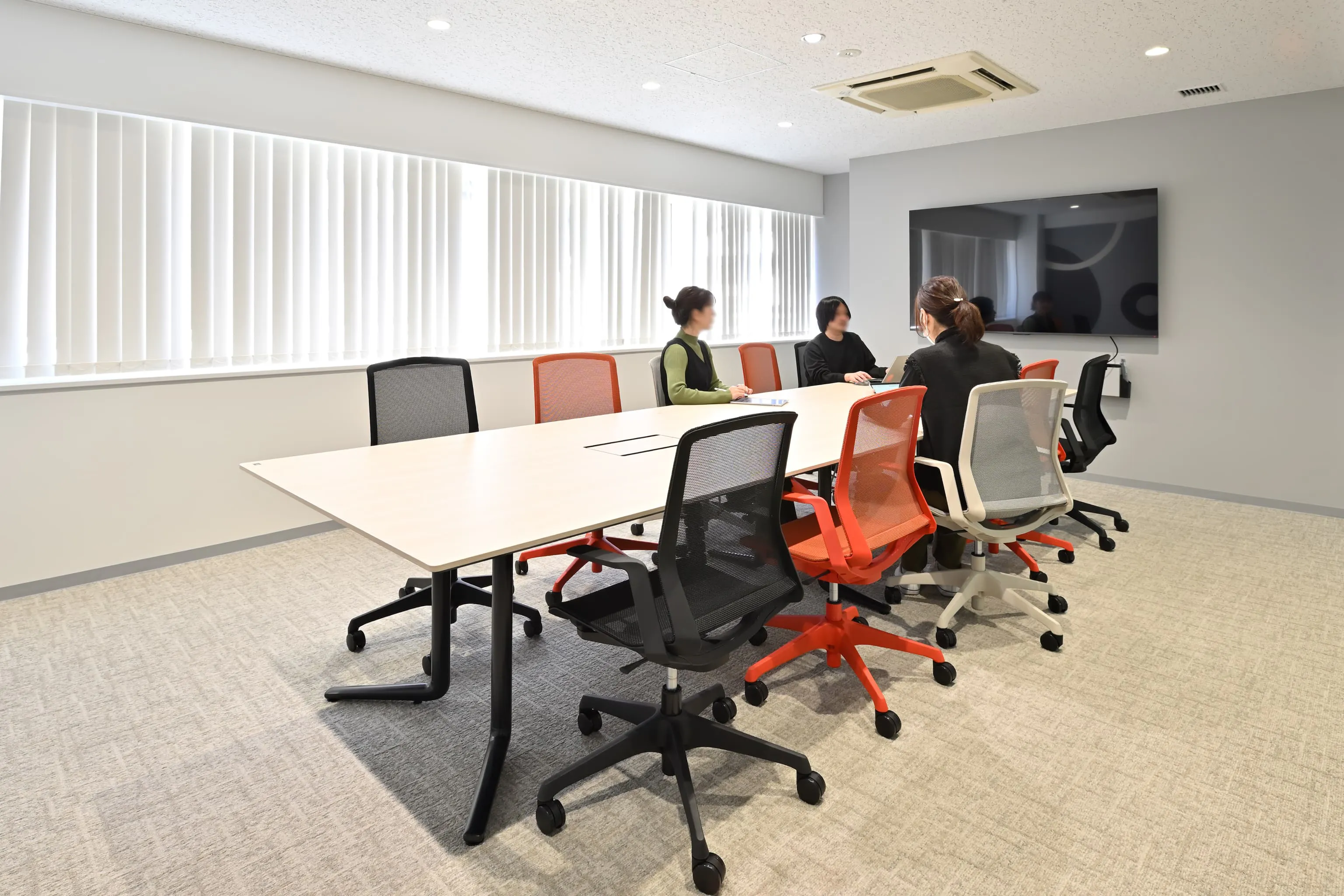 株式会社岡本工作機械製作所 様の事例写真／[1F会議室]コーポレートカラーの赤や、工作機械の黒とグレーのチェアを配した会議室は、広さの異なる計6部屋を備えています。少人数から大人数まで会議の規模に合わせた使い分けが可能です。商談だけでなく、社内ミーティングにも幅広く活用されています。