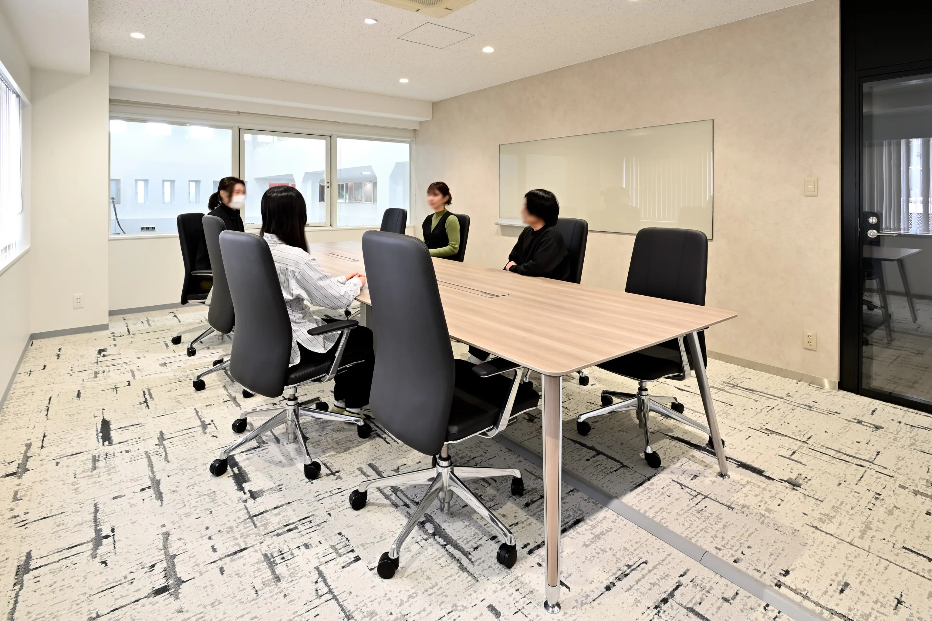 株式会社岡本工作機械製作所 様の事例写真／[1F VIPルーム]上質な什器が選定され、品格を感じられる空間。ガラスの壁面ホワイトボードが、デザインコンセプトである先進性をさりげなく表現しています。洗練と安らぎを大切にしたおもてなしの設えが、信頼関係の構築を後押しします。