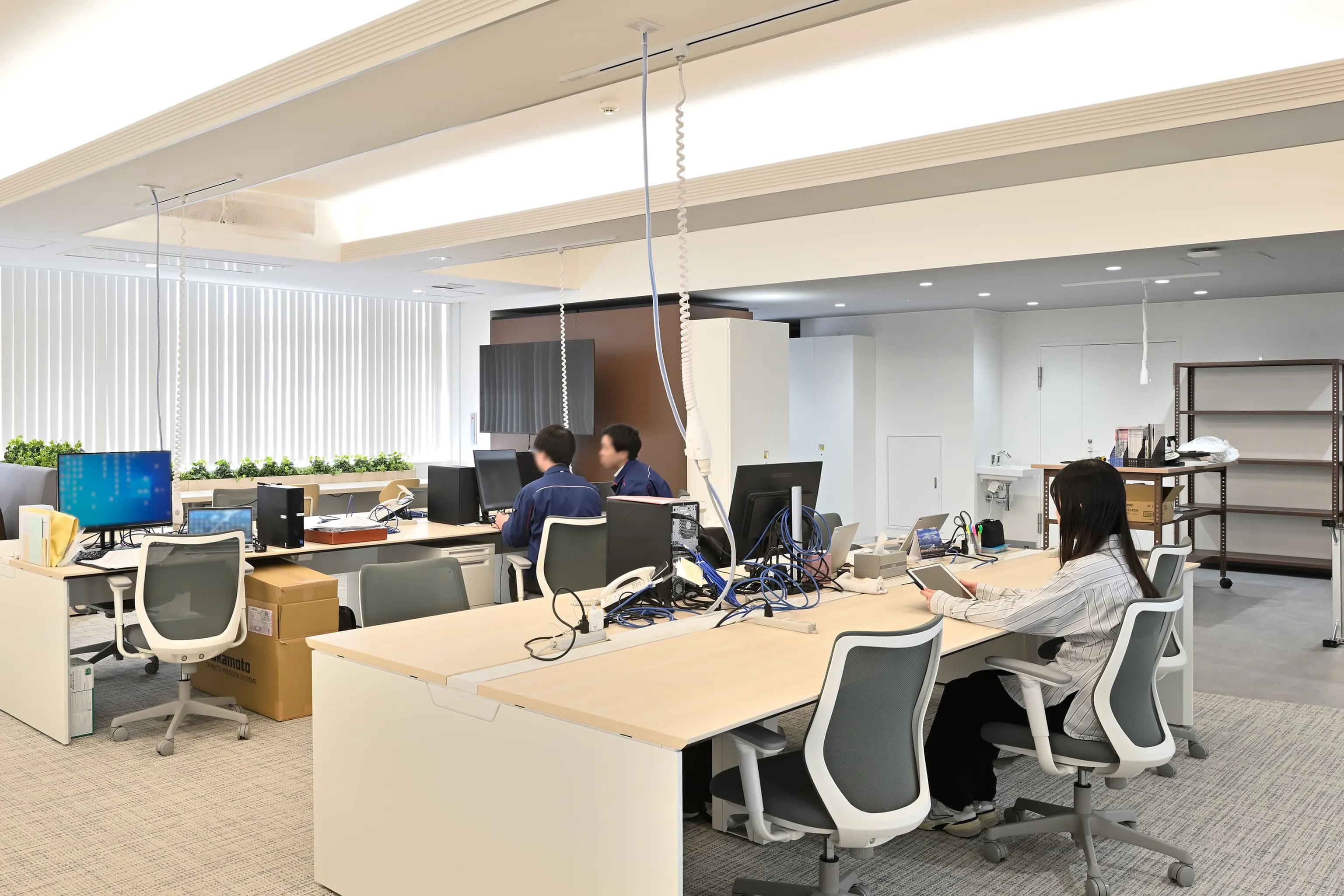 株式会社岡本工作機械製作所 様の事例写真／[2F執務エリア]OAフロア化の工事は行わず、電源はOCポータブルバッテリーと天井からの配線で確保。コストを抑えつつ、レイアウト変更にも柔軟に対応できる環境が整えられています。
