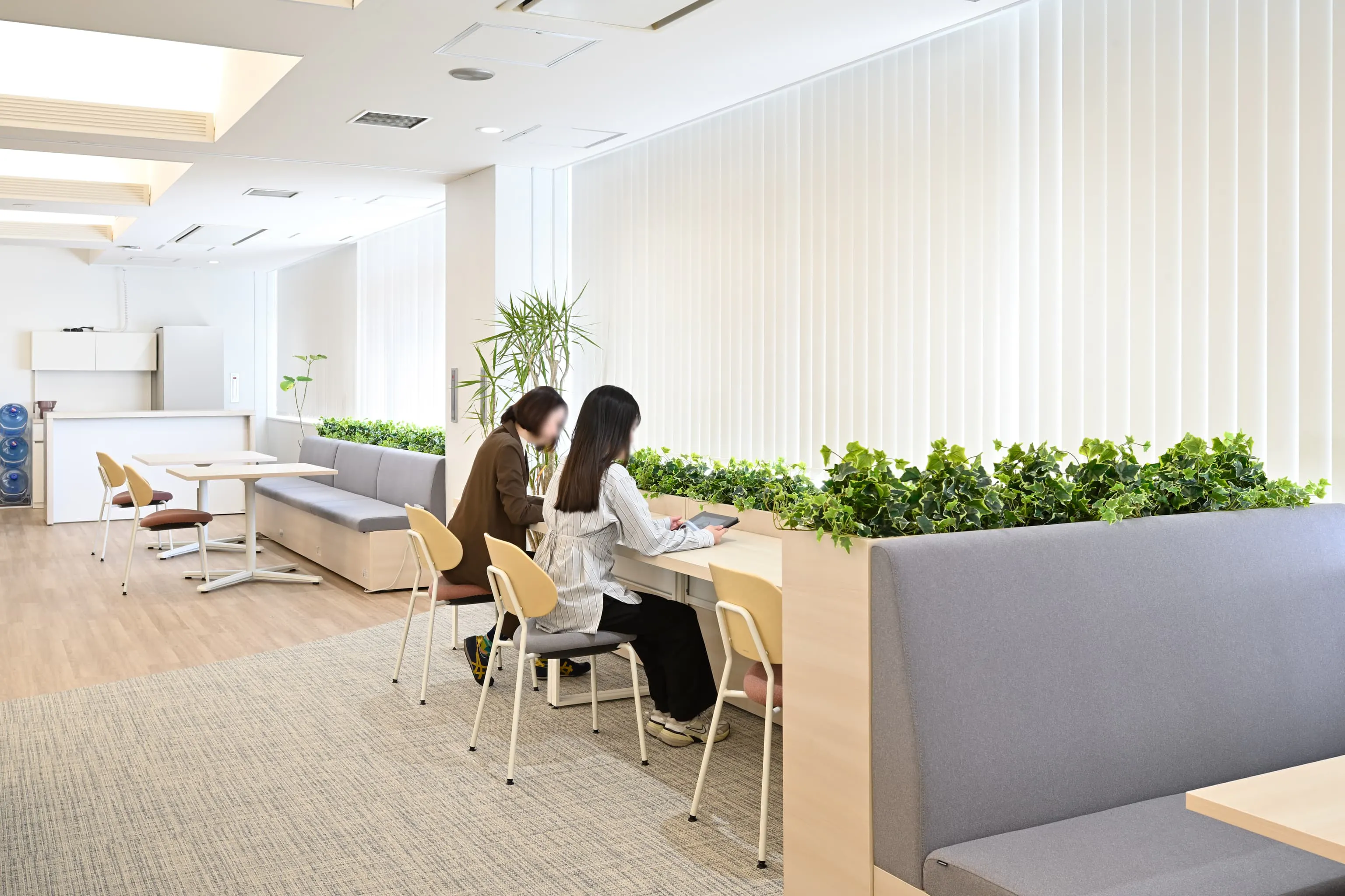 株式会社岡本工作機械製作所 様の事例写真／[2F執務エリア]カウンター席は、個人作業に集中したいときに適したスペースです。目の前の植栽が仕事の合間に安らぎをもたらします。本社から訪れた社員からは、これまでとは異なる空間の印象に新鮮さを感じたという声も聞かれます。