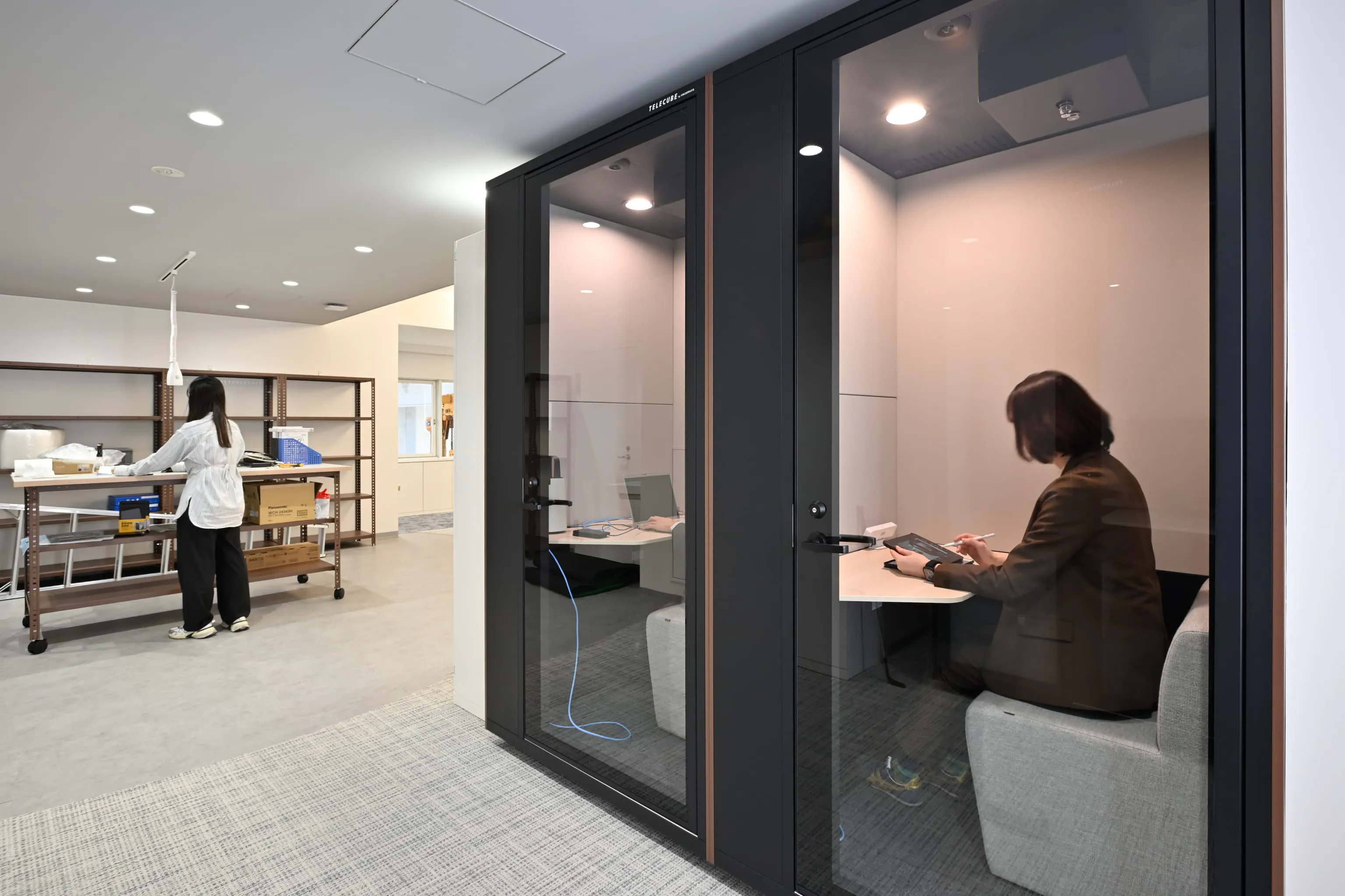 株式会社岡本工作機械製作所 様の事例写真／[2F WEBブース]オンライン商談や会議に対応するフルクローズ型ワークブース。1人利用でも大きな会議室を占有せずに済み、空間の有効活用と音への配慮を両立。本社との連携もスムーズになり、働きやすい環境づくりに役立っています。