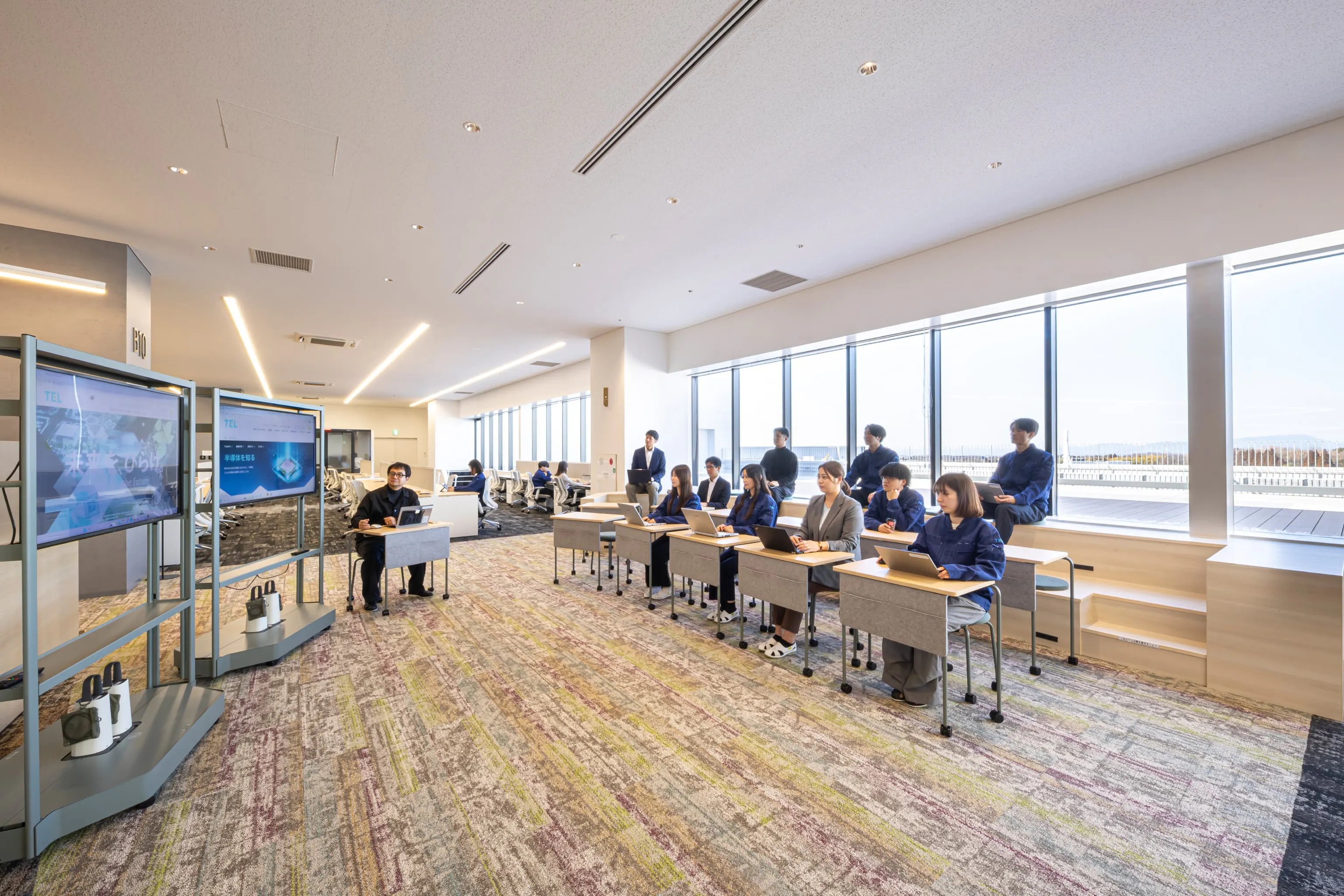 東京エレクトロン九州株式会社 様の事例写真／[4F執務エリア]執務エリアの最奥には、ステップベンチと可動式のデスクとチェアを組み合わせた交流スペースがあります。人数に合わせて柔軟にレイアウトを変更でき、勉強会や打ち合わせなど多目的に活用されています。