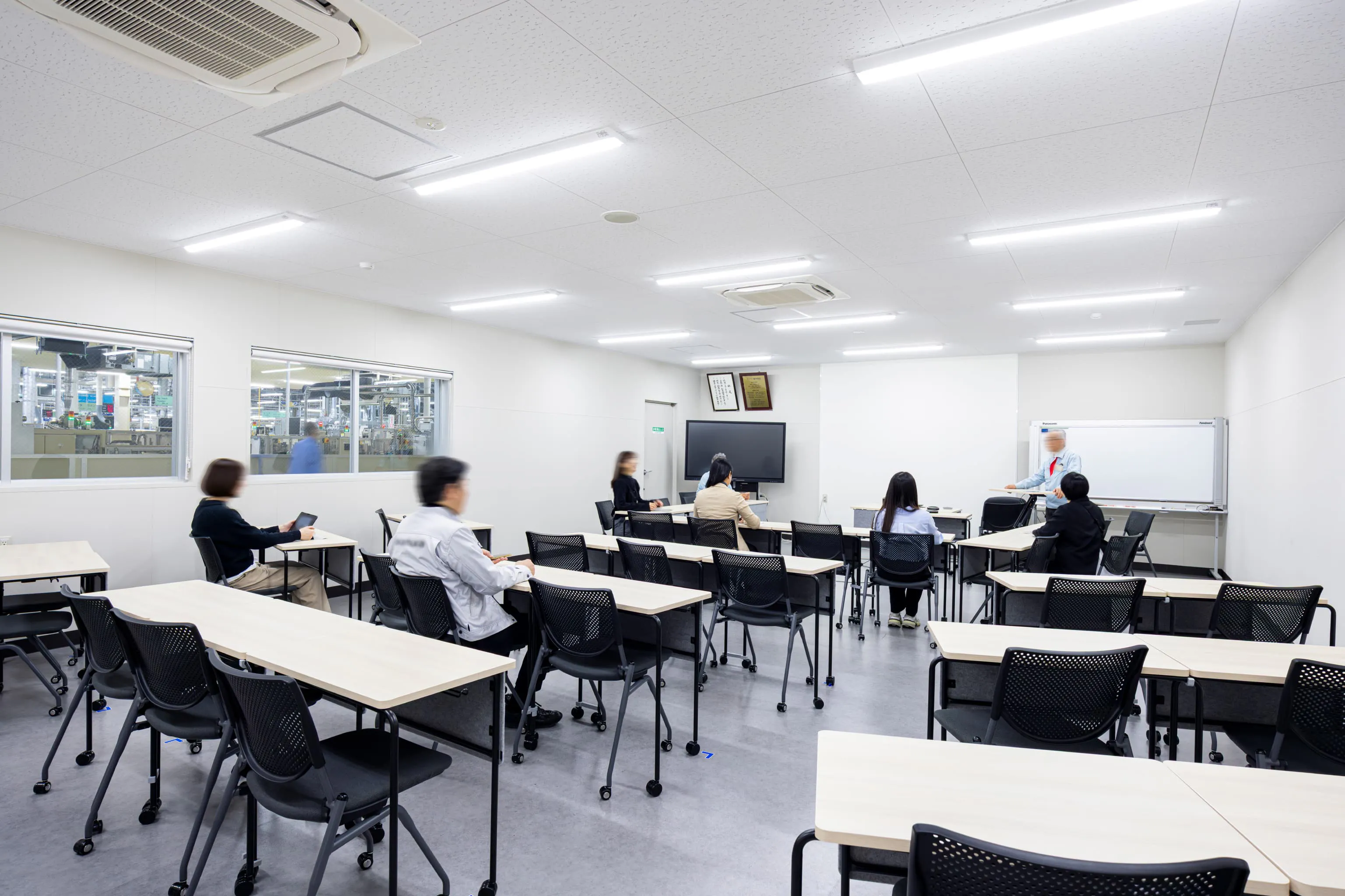 株式会社デンソー安城製作所 様の事例写真／[1F 大会議室]40人まで入る大会議室は、隣接する工場内をガラス窓から見渡せます。工場から出入りすることを想定し、汚れにくい床材を採用。可動式什器が配され、利用人数やシーンに合わせて素早くレイアウトを変えられます。