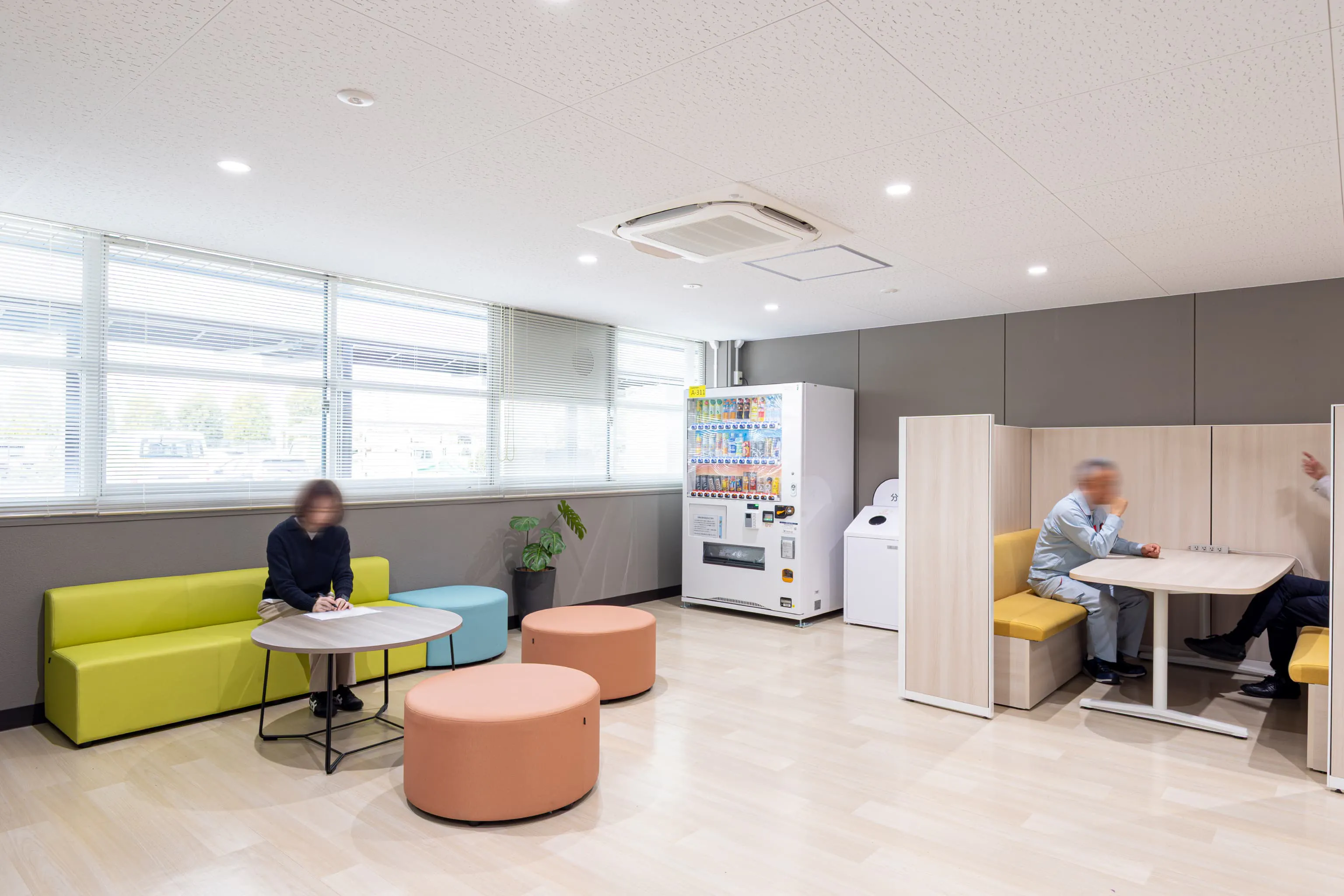 株式会社デンソー安城製作所 様の事例写真／[1F多目的ロビー]1F多目的ロビーの一角には自動販売機とカラフルなソファが並び、従業員が気軽に休憩できるスペースに。ファミレス席は、協力会社との打ち合わせや来客の待合スペースとして使われています。