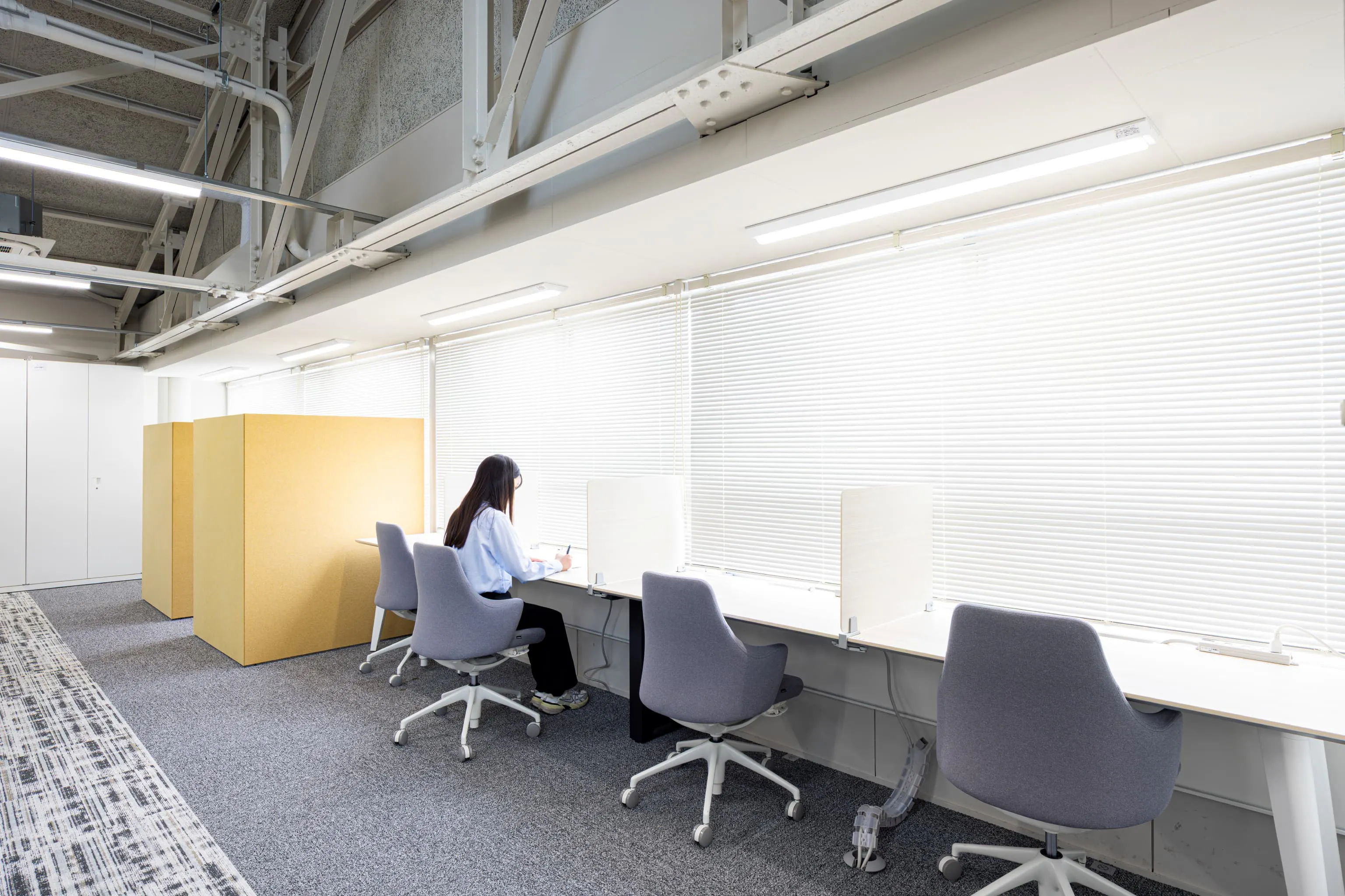 株式会社デンソー安城製作所 様の事例写真／[2F執務エリア]執務エリアの窓際には、集中して作業ができる席が並びます。柔らかい陽の光に包まれながらリラックスして働けるため、気分転換に使う人も多いエリアです。