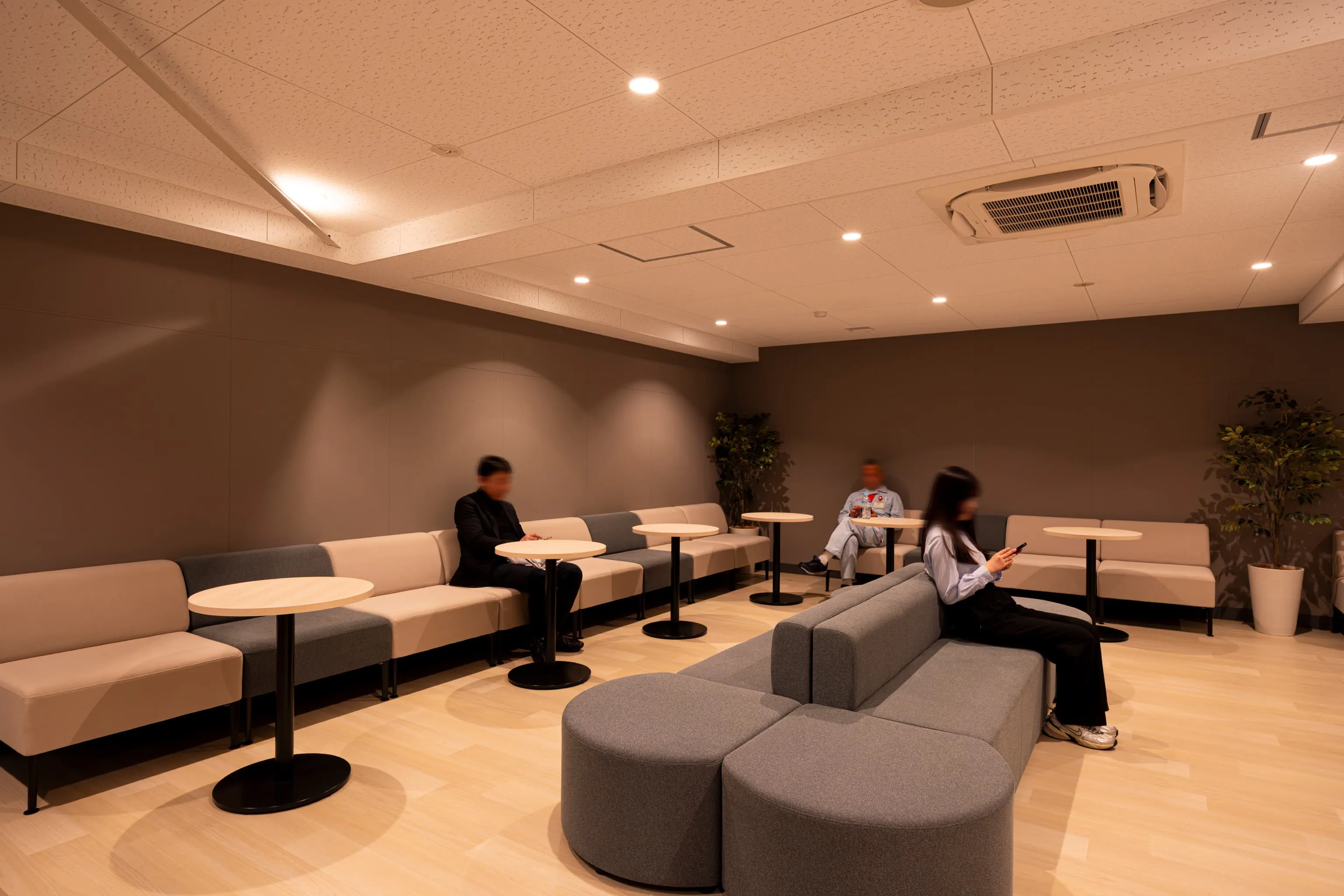 株式会社デンソー安城製作所 様の事例写真／[2F憩いのコーナー]憩いのコーナーは、業務から離れて一息つける休憩スペースです。執務エリアとは異なる温かみのある照明で自然と気持ちが切り替わります。遊び心のある曲線型のソファはいろいろな角度で座れて、周囲の人と会話しやすいと好評です。