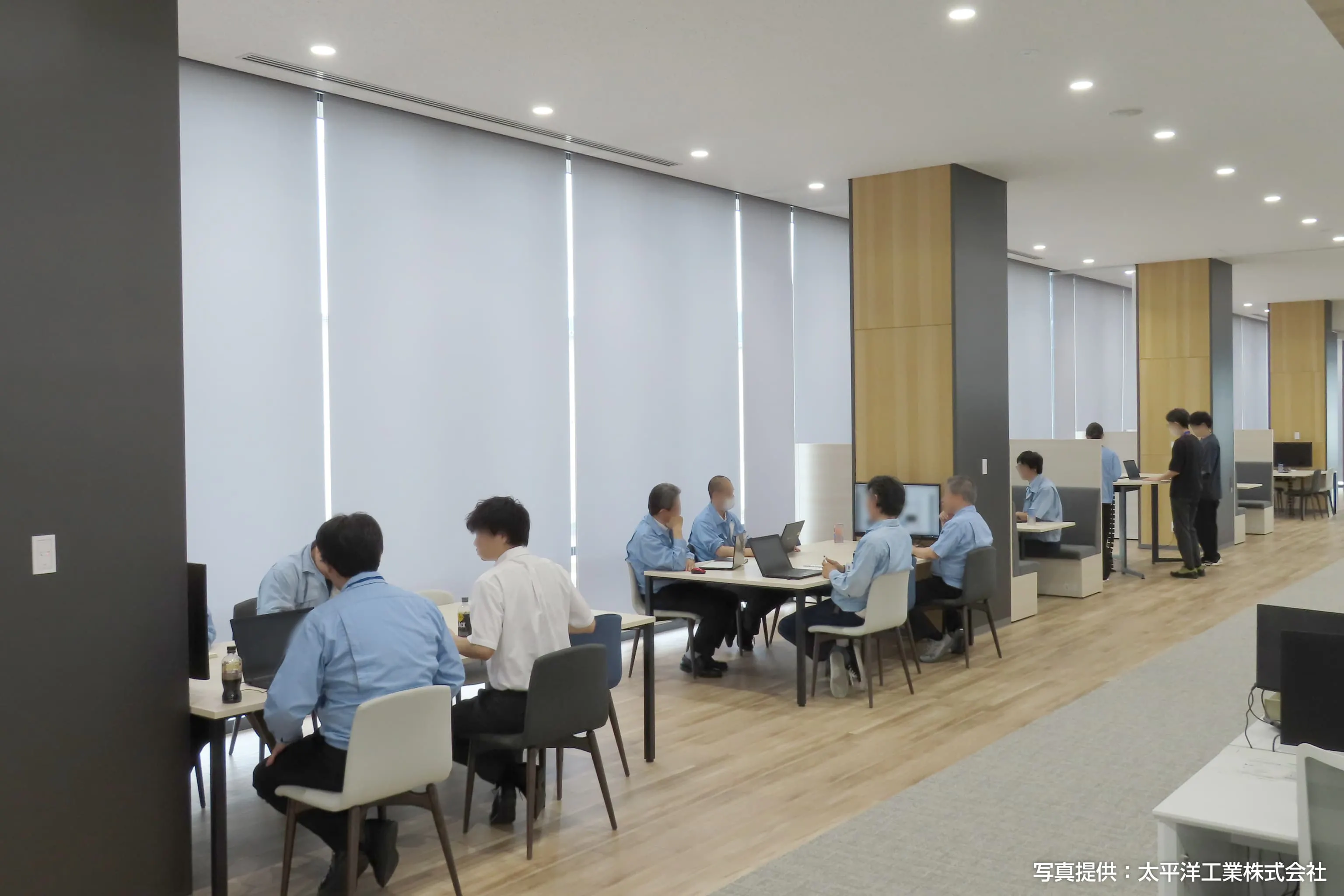 太平洋工業株式会社 様の事例写真／[2Fワイガヤエリア]柱のデザインと統一感のある、黒や木目の脚を用いたテーブルとチェアを採用。モニターを使ったミーティング、図面を広げての確認作業など、目的に応じて席が選ばれています。