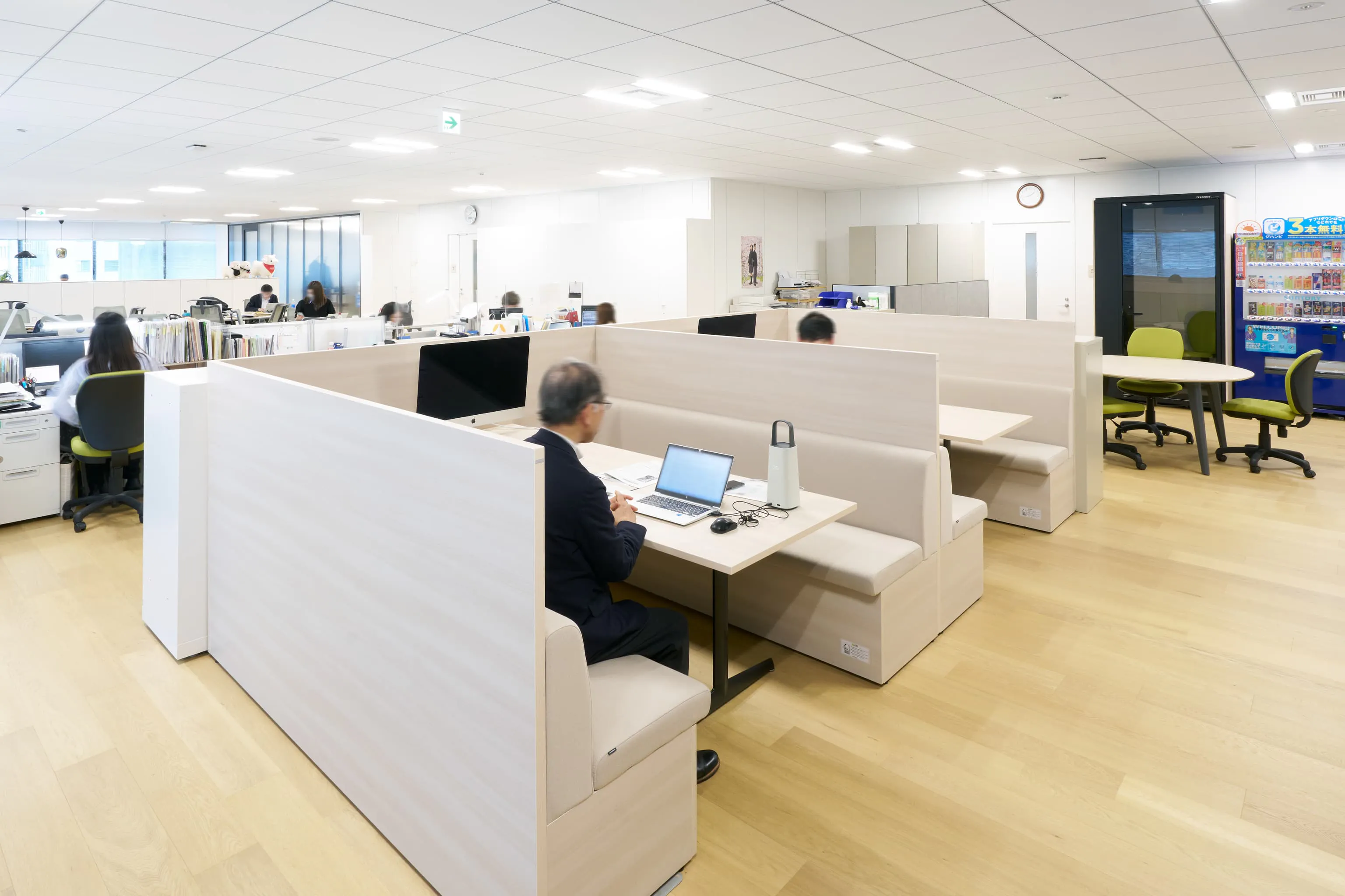 日本毛織株式会社 様の事例写真／[3F執務エリア]ファミレスブースは、大判資料の作成やサンプル生地を広げる作業にも使いやすい場所です。OCポータブルバッテリーにより、電源の位置を気にせず働ける点も好評。ソファの座面下は空洞になっており、備品を収納できます。