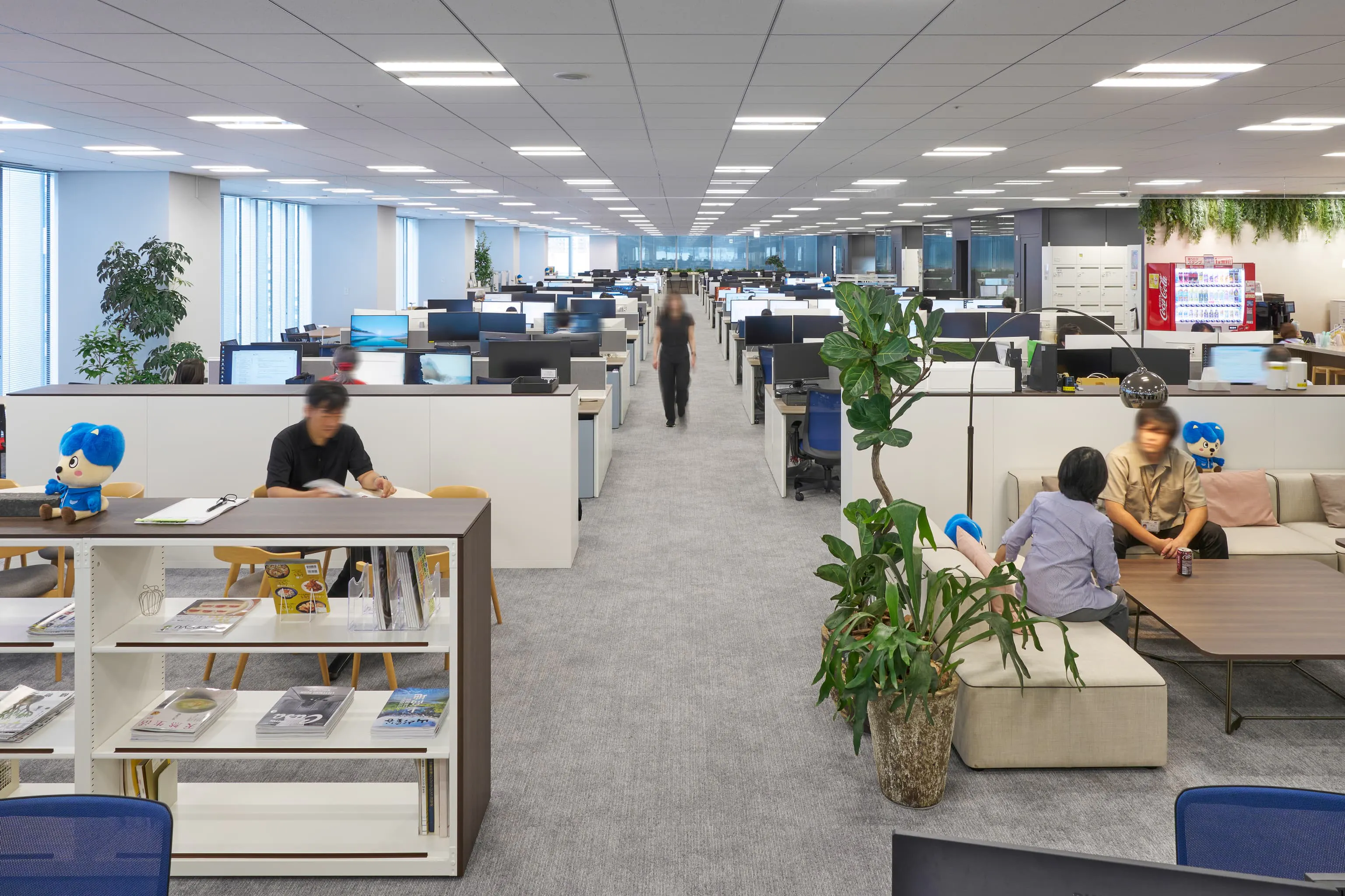 三菱電機エンジニアリング株式会社 様の事例写真／[9Fカフェエリア]カフェエリアの両側には執務エリアが広がります。低いシェルフでゾーニングされ、集中と交流がゆるやかに共存。見通しがよい空間は、人の動きや気配が伝わりやすく、自然な交流が生まれています。